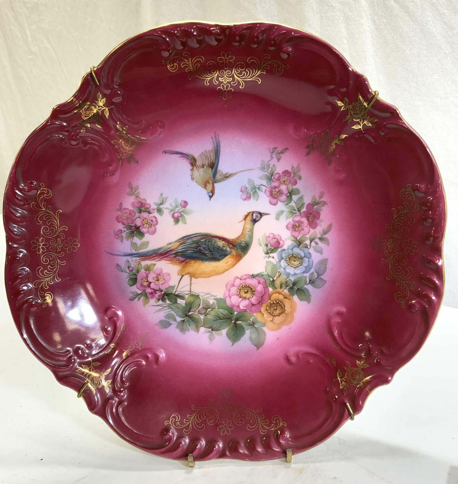 CICO Bavaria Pheasant Porcelain Display Plate: CICO Bavarian Hand Painted Pheasant and Floral Porcelain Plate . Painted Cranberry with gilt accents. Center image of 2 colorful pheasants encircle in colorful flowers. Cisco Trademark on verso, Made 