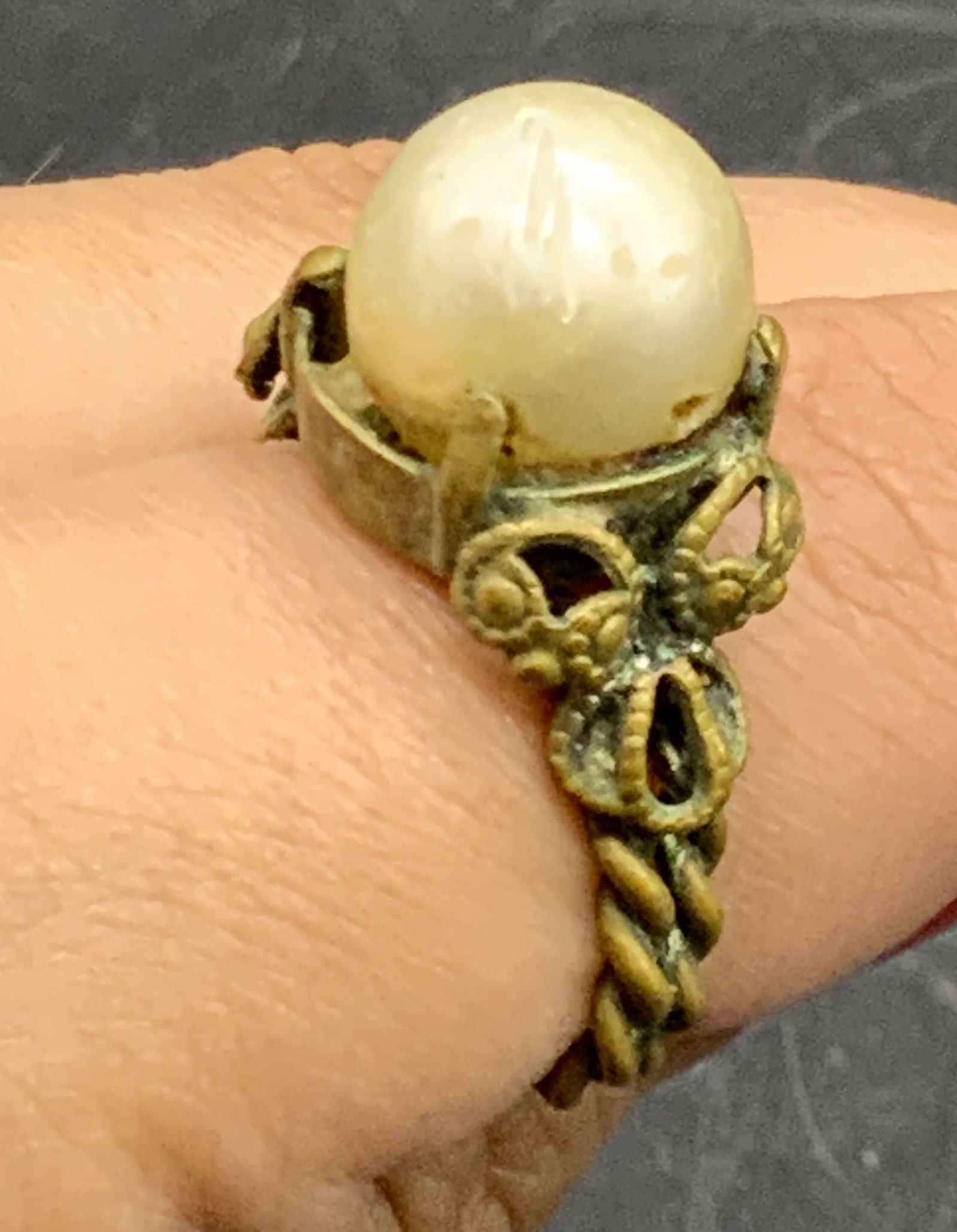Vintage Pearlescent Solitaire Ring, Jewelry: A vintage pearlescent solitaire ring with a brass hued metal band. Rope motif to the band Approx. Size 7. Patina, discoloration, and surface wear present. Drilled holes to the sides of the composite p