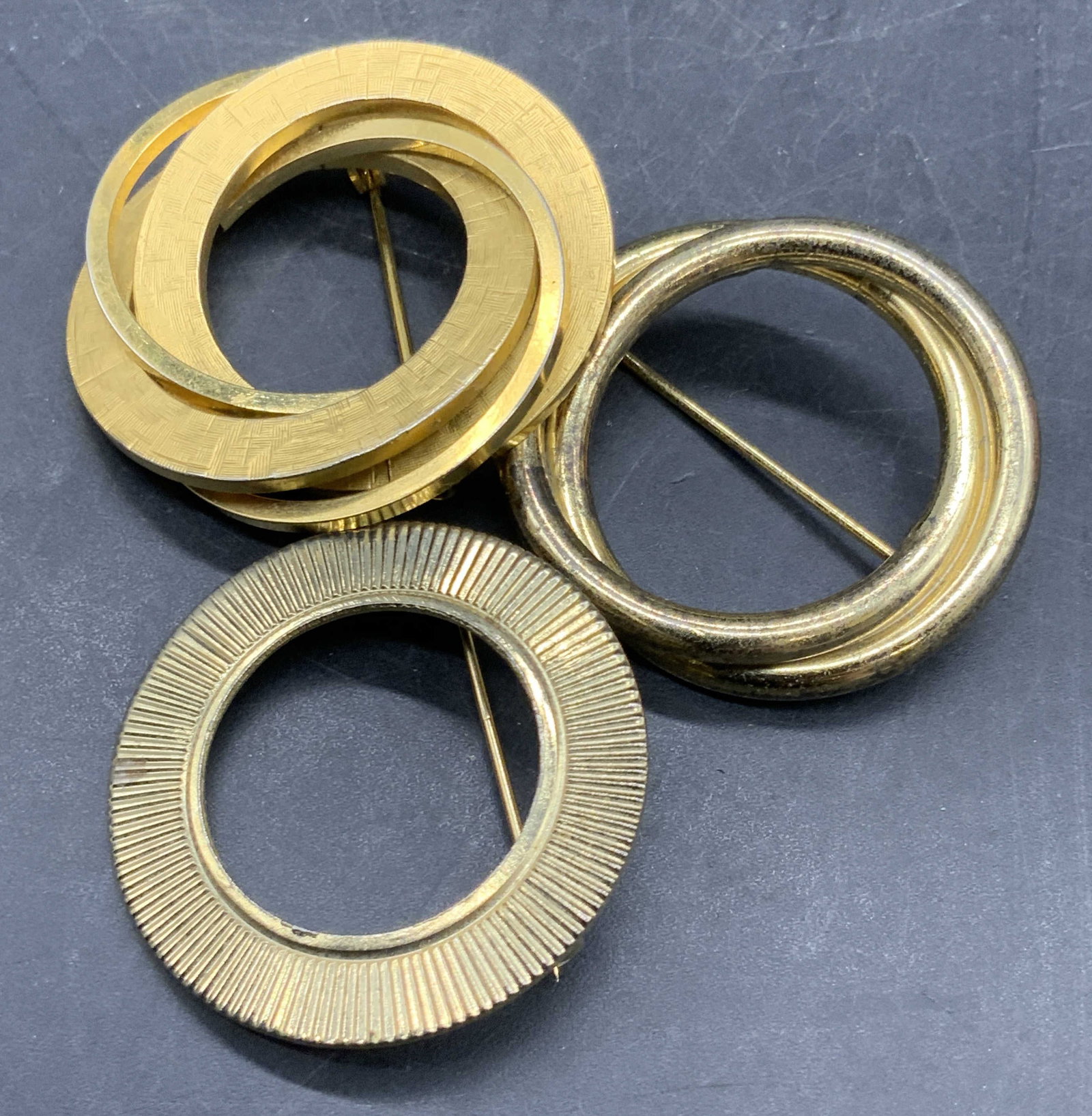 Lot 3 Vintage Circular Brooches, Sterling Silver +: Three vintage gold tone circular brooches. One is gold filled, one is sterling with a gold tone finish, and the other is crafted from gold tone metal. Two pieces are signed WINARD 12K GF and STERLING 