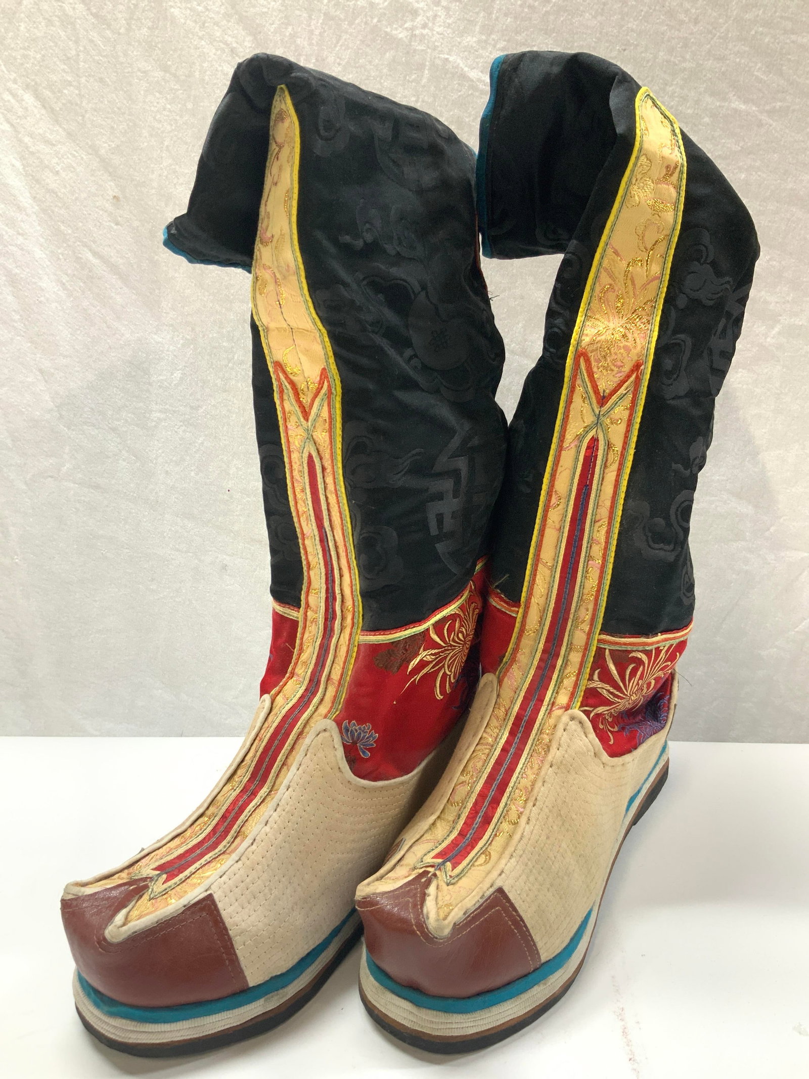Vtg Leather & Textile Crafted Bhutan Boots: Pair of vintage traditional crafted Bhutan boots/ Mongolian boots. Crafted from leather, woven fibers and with sewn Asian textiles and gold toned threading. Approx 18 inches tall, with a sole of 10.5 