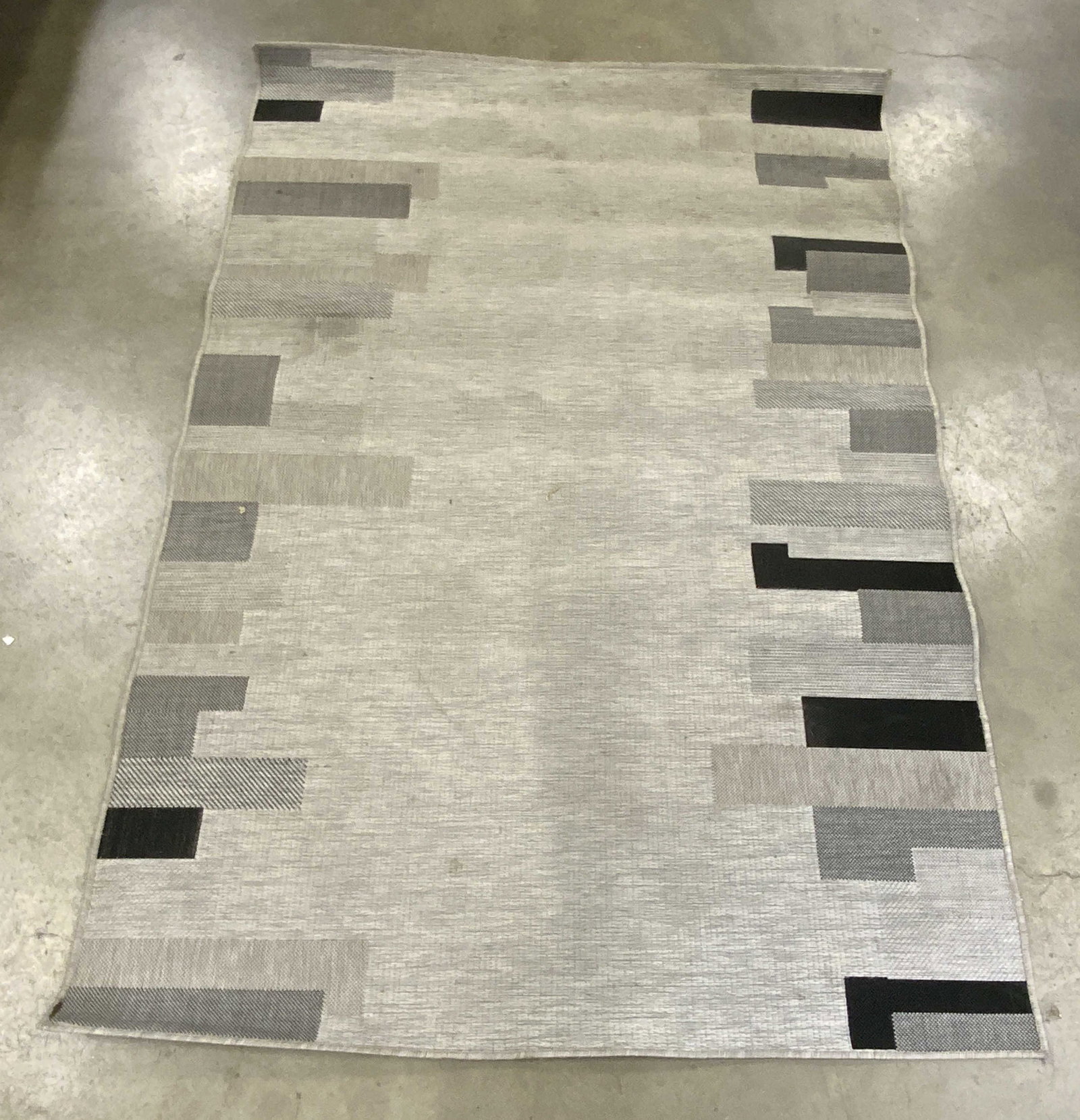 JAIPUR Nikea Silver / Charcoal Rug: A silver gray and charcoal hued rug. Geometric patterns to the obverse. Tag to underside reads JAIPUR, NIKEA, OASIS, SILVER / CHARCOAL. Crafted from manmade material. Measures approx. 90L x 62W in. Di
