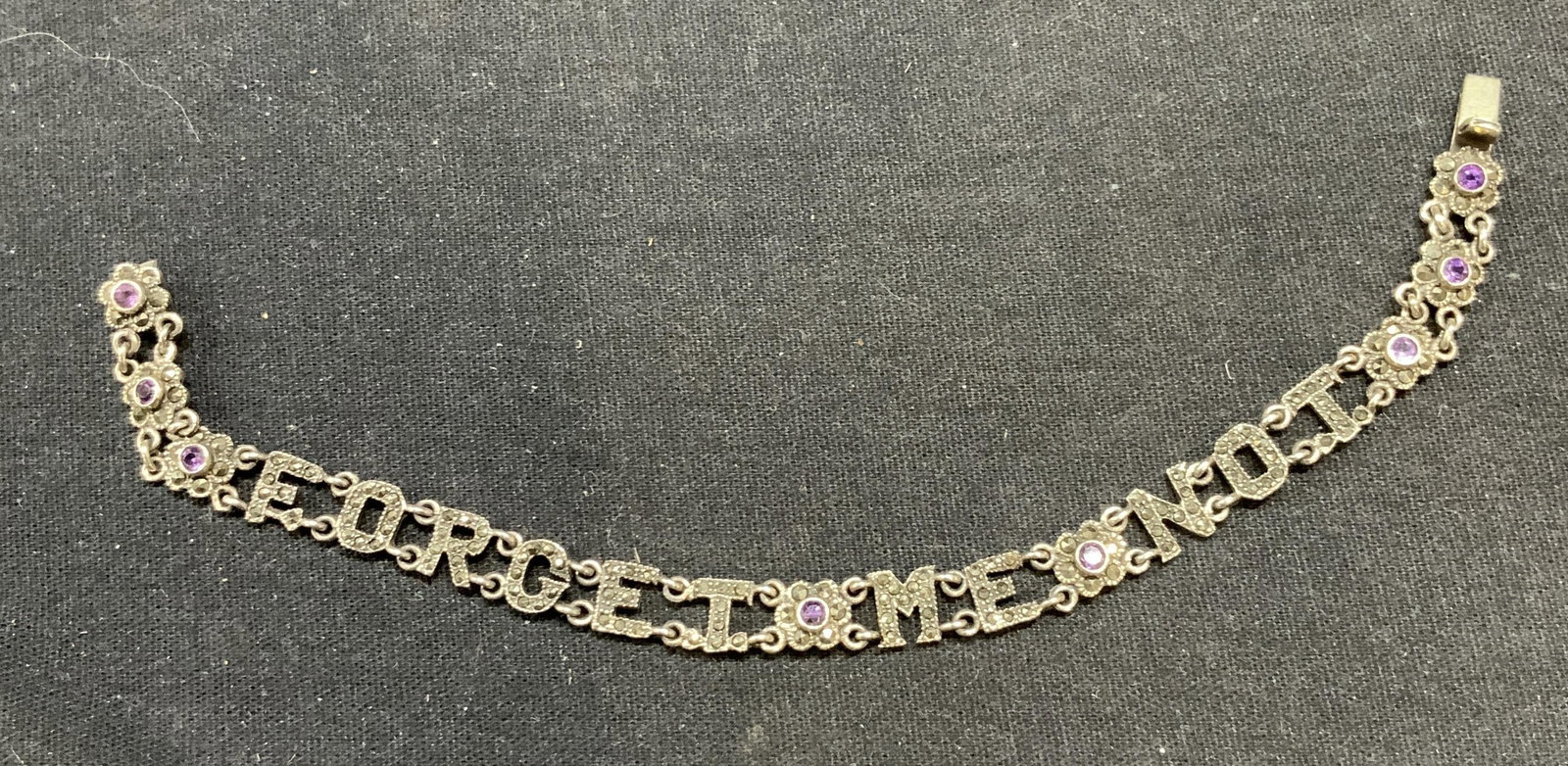 Sterling Silver Amethyst Forget Me Not Bracelet: Vintage sterling silver, amethyst, and Marcasite decorated Forget Me Not bracelet with floral motif. Marked sterling to underside. Measures approx. 7.5 inches long. Total weight 11.1 grams. Some surfa