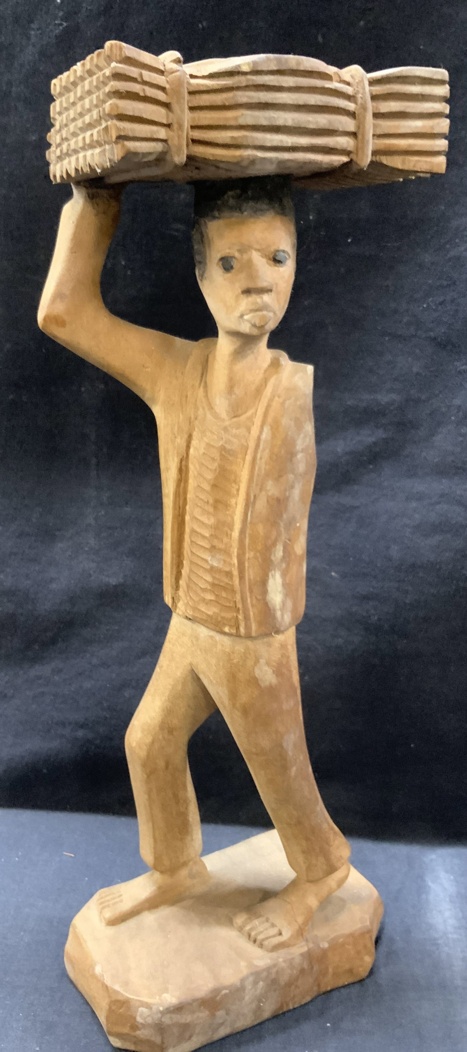 E.Jeanty Sgd Wooden Carved Figure: Carved wooden figure of a one armed man holding a bundle of straw on his head. Marked on underside E.jeanty. Approx 14 inches tall with a 5 x 3 inch base Moderate wearing to wood throughout, lack of f