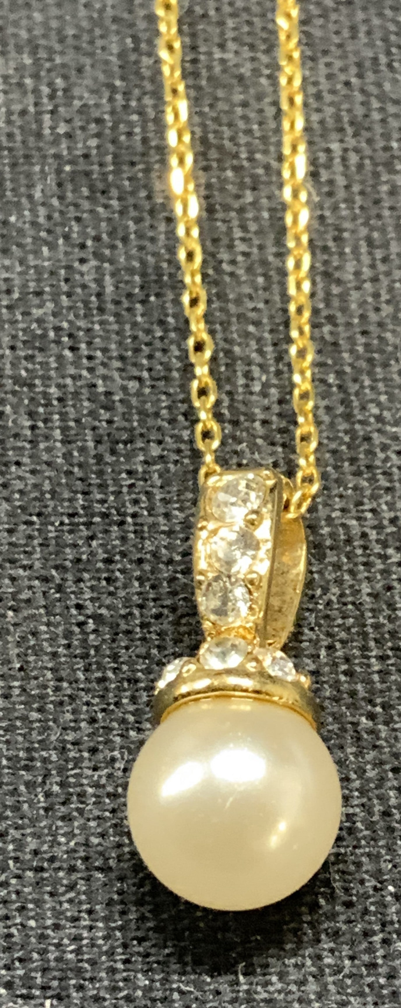 Hallmarked Gold Tone Faux Pearl Necklace: Hallmarked gold tone pendant necklace with faux Pearl and crystal. Hallmarked illegibly on clasp. Drop length approx. 7.75 inches. Some surface wear including scratching observed. Estate jewelry, cost