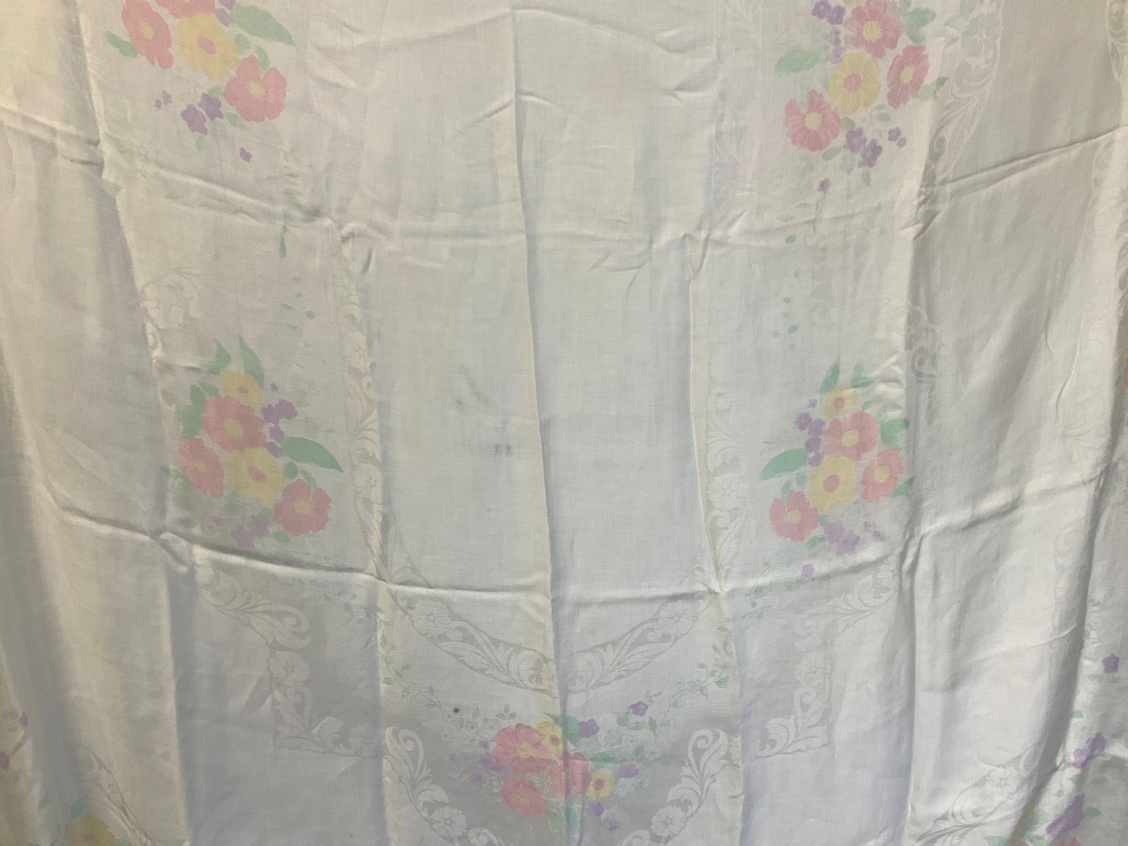 Vntg Floral Cotton Tablecloth: Vintage cotton, possibly silk white tablecloth with printer motifs of colored flowers along with scroll motifs throughout the white cloth. Approx 68 x 124 inches Minor wearing to cloth and Material Ho