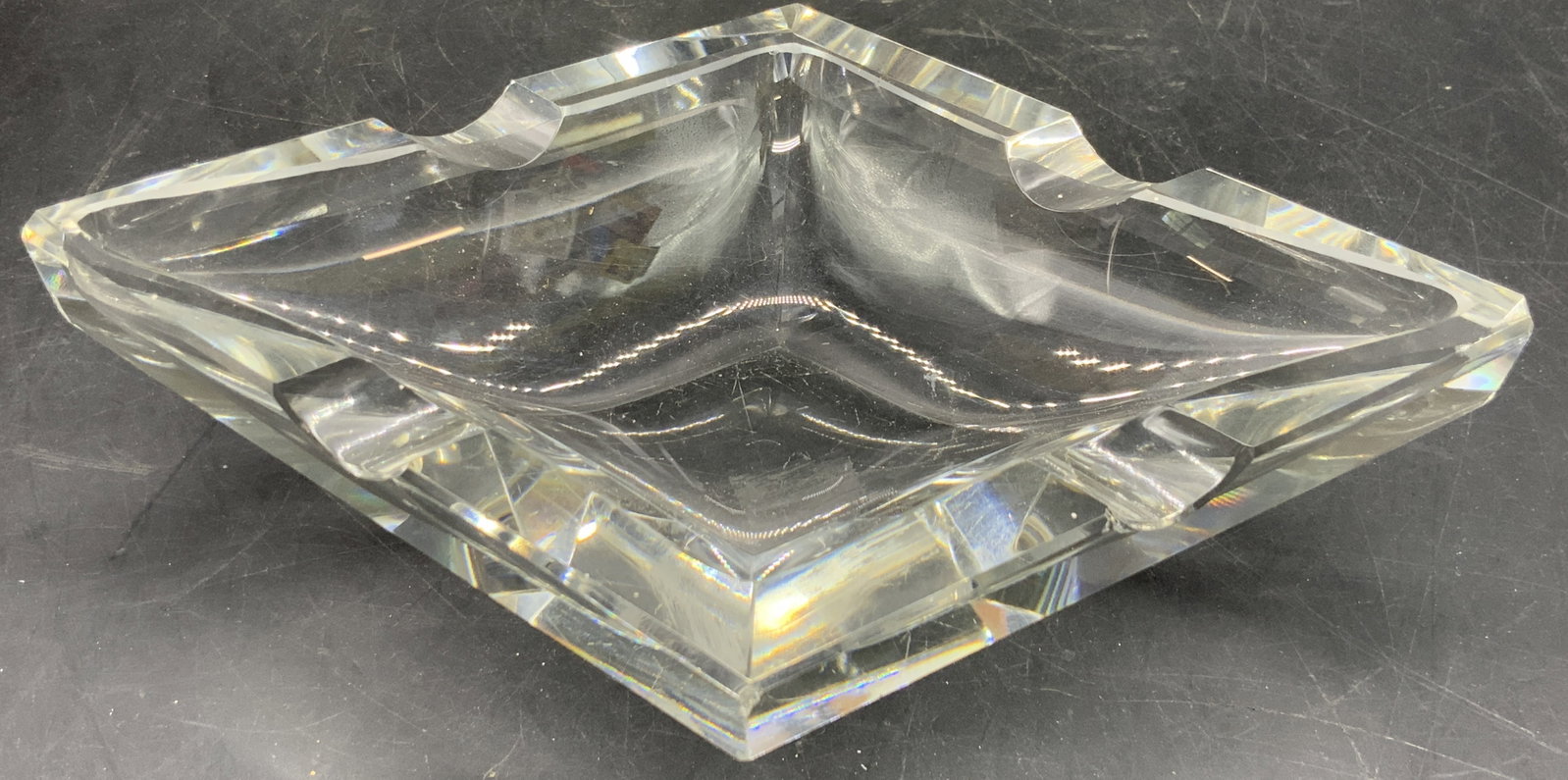 Diamond Form Clear Art Glass Trinket Dish: A diamond form clear art glass trinket dish / ashtray. Thick walled and weighty. Divots to the rim. Measures approx. 1.75H x 8W in. Measured at widest point. Chipping and surface wear present. Sticker