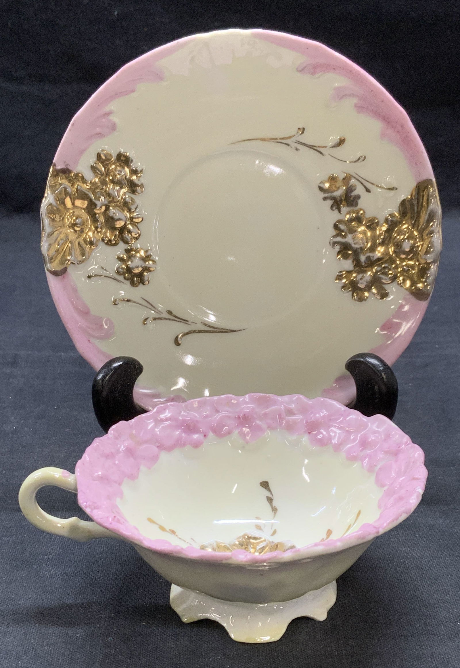 Vintage Gilt Floral Pink Teacup & Saucer: Vintage gilt pink and white porcelain tea cup and saucer with floral motif. Saucer measures approx. 5.25 inches wide. Teacup measures approx. 3.75 x 1.75 inches. Both pieces have some surface wear inc