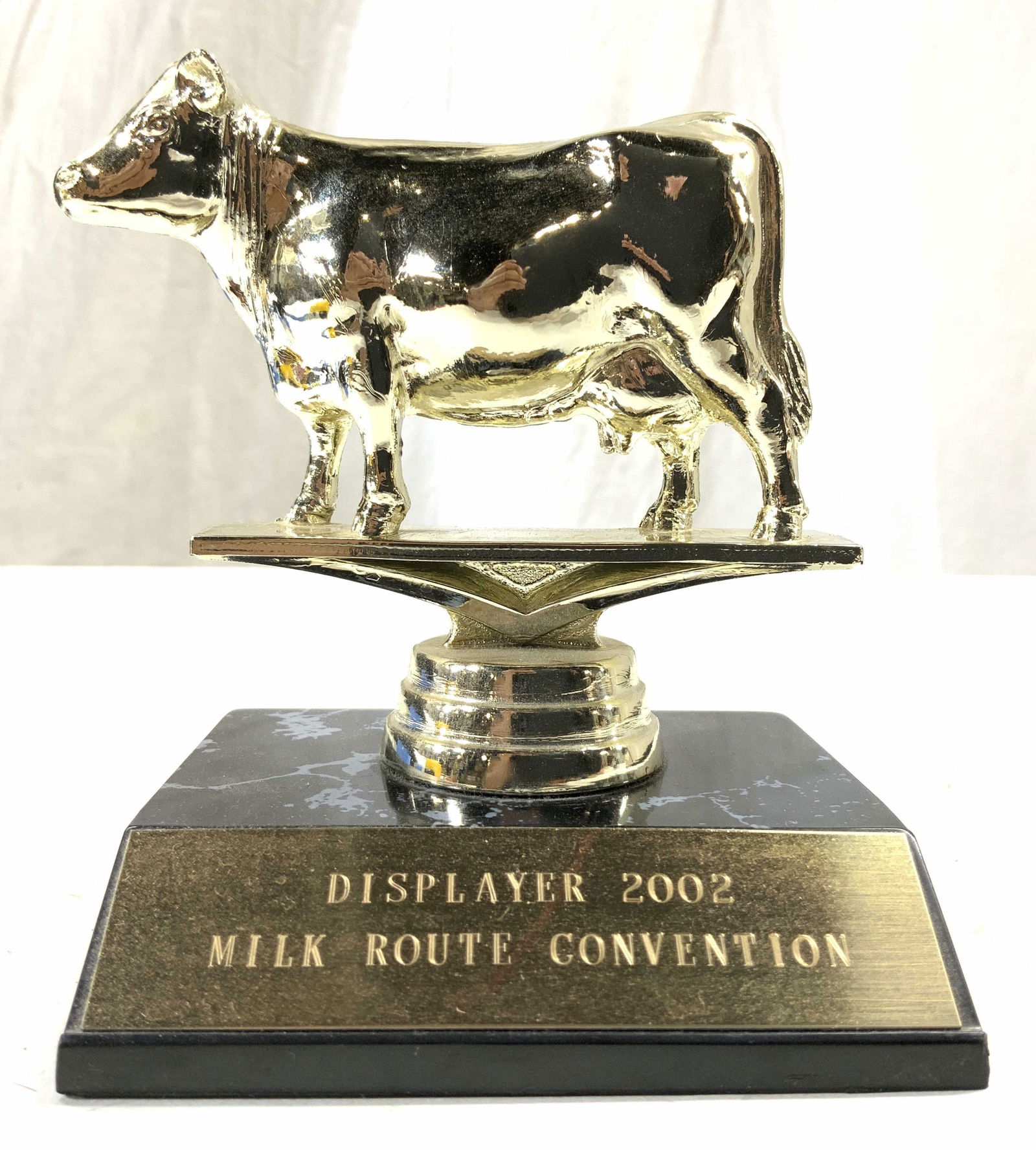 DISPLAYER 2002 MILK ROUTE CONV Trophy: Trophy plaque reads DISPLAYER 2002 MILK ROUTE CONVENTION. Underside reads DINN BROS. Trophy has cow figural. Piece measures approx 4.5 inches tall 3.75 inches wide 3 inches deep. Trophy, cow trophy, D