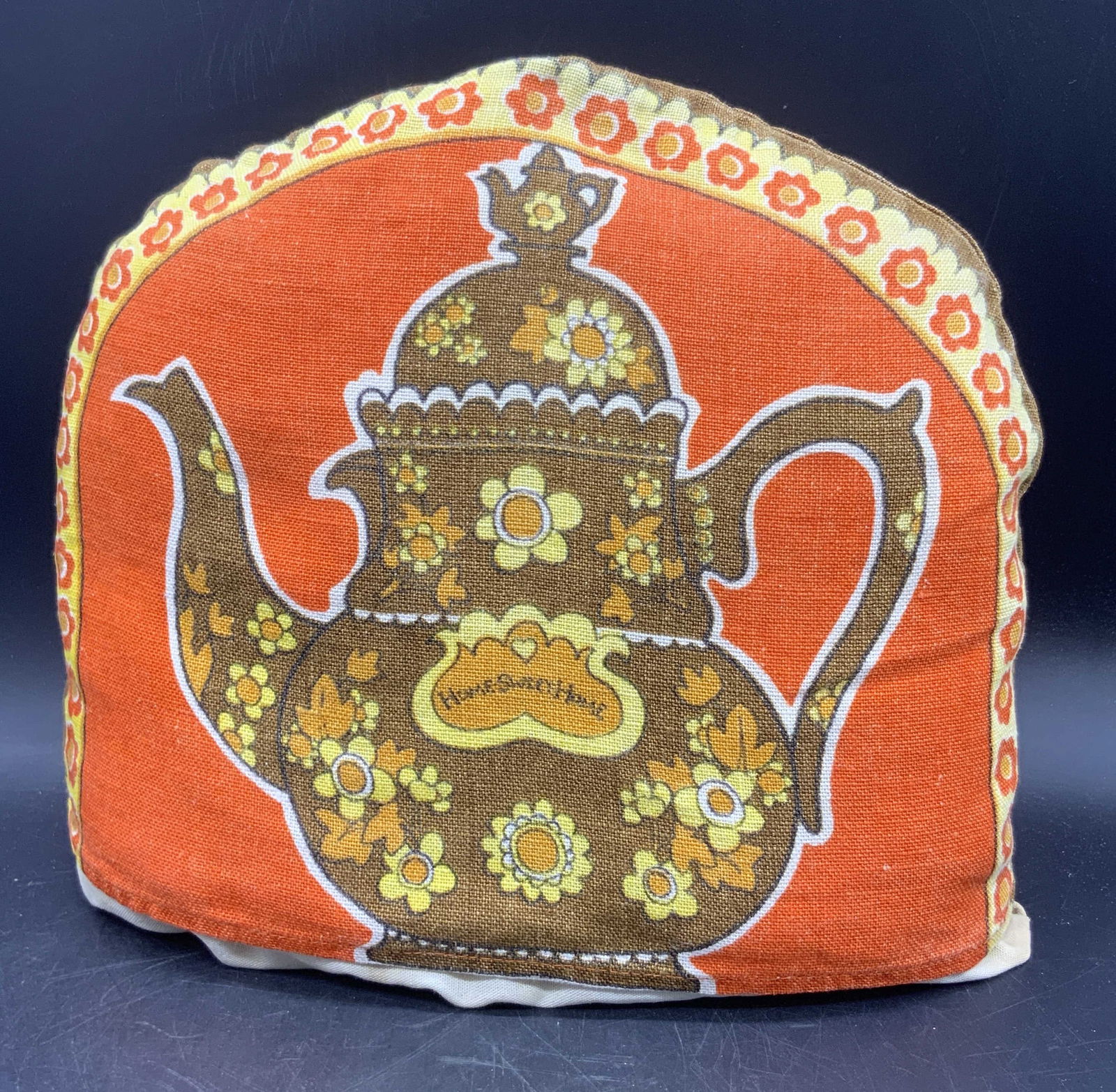 Vintage Home Sweet Home Teapot Motif Kettle Cover: A vintage fabric kettle / teapot cover decorated with a teapot motif. Lettering reads HOME SWEET HOME. Orange, yellow, brown, and black hues throughout. Measures approx. 10L x 11.25W in. Some surface
