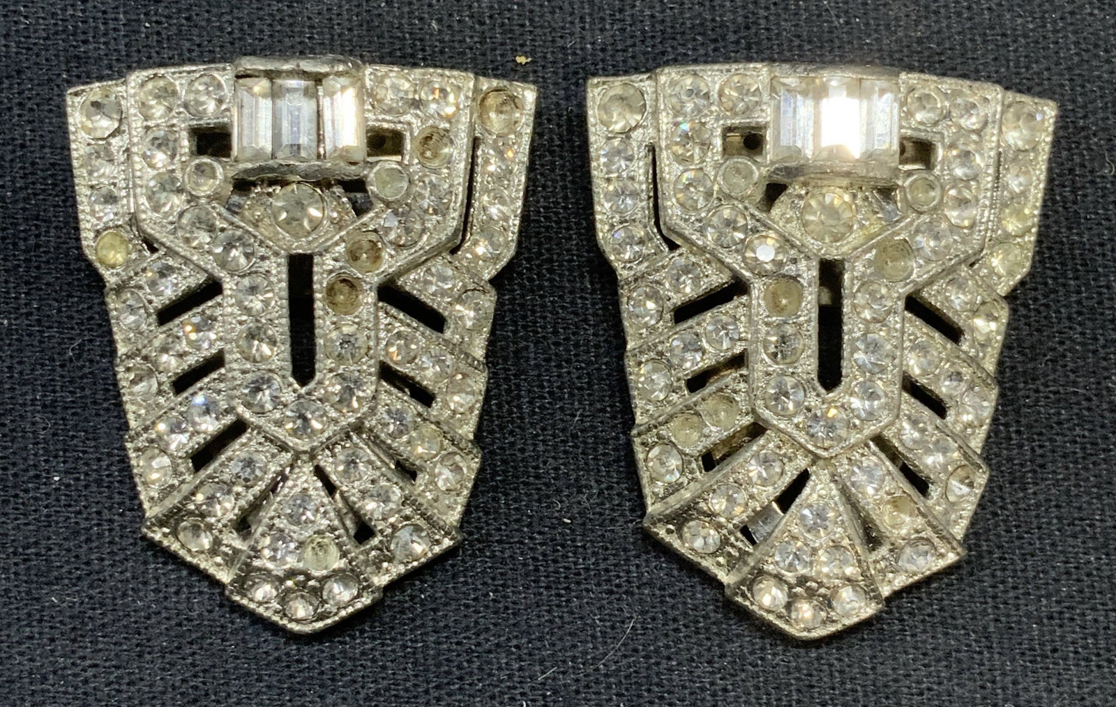 Pair Vintage Silver Tn Crystal Dress Clips: Pair of vintage silver tone and colorless crystal decorated dress, sweater, or scarf clips. Measure approx. 1 3/8 x 1 1/8 inches each. Some surface wear including scratching observed to each. Some cry