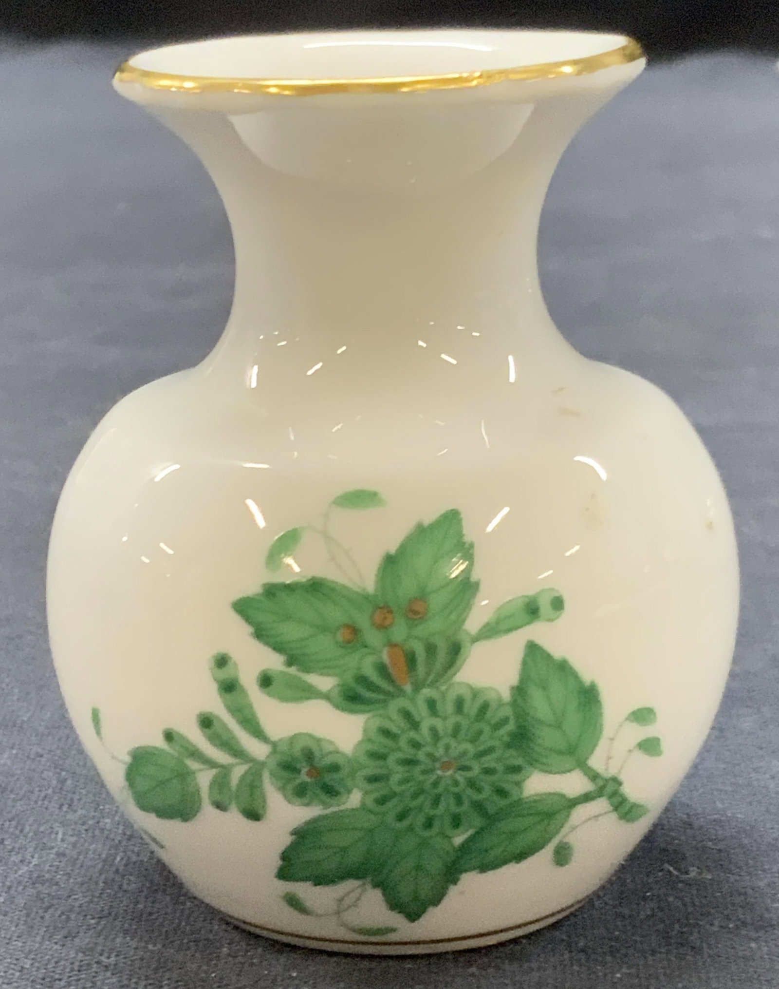 HEREND Hand Painted Porcelain Vessel, Germany: Marked on underside, Herend, hand painted, made in Germany. White porcelain vessel with gilt rims and green painted florals on sides. Approx 3 inches tall. Minor surface wearing to porcelain due to ag