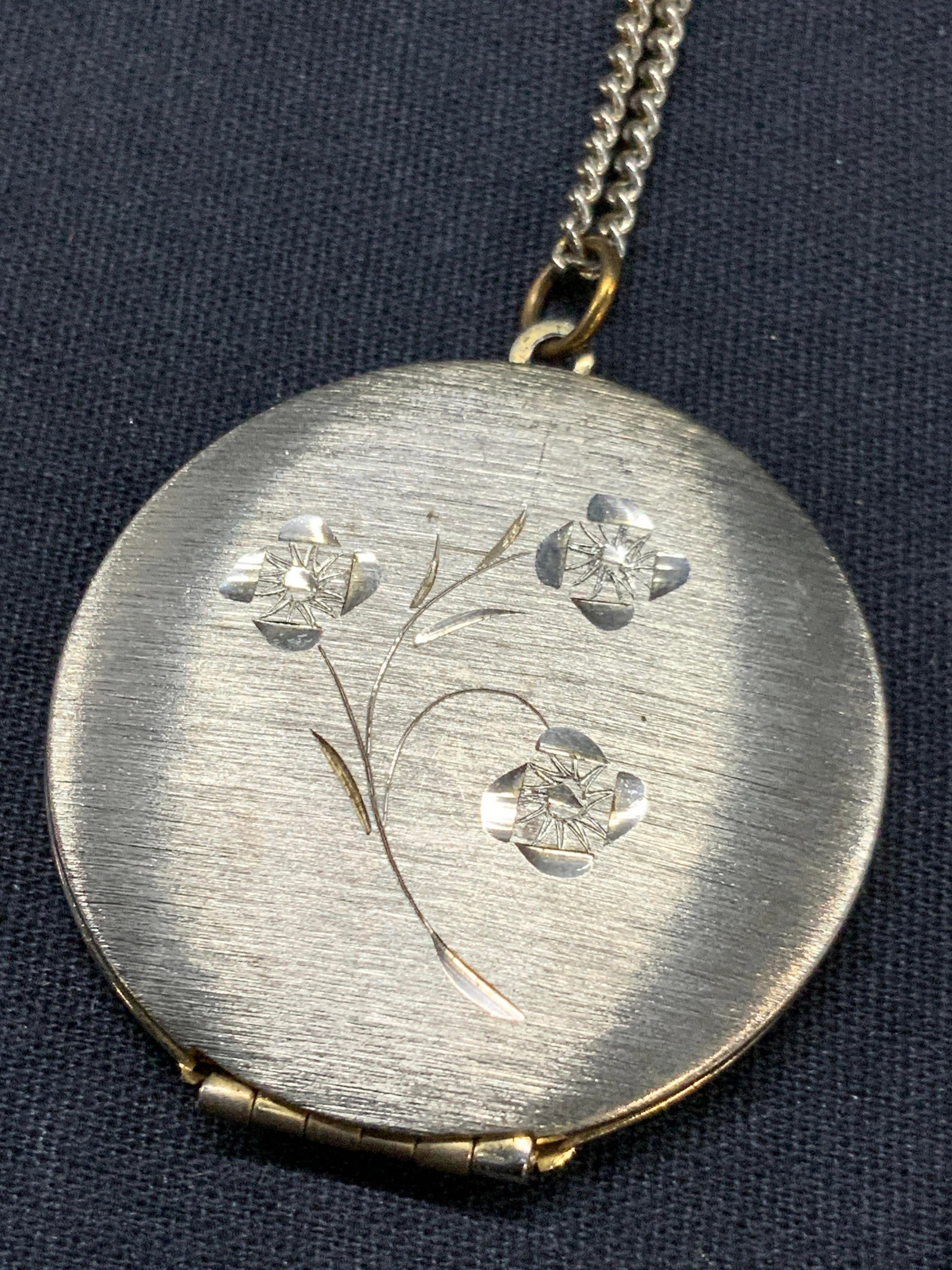 Silver Plate Etched Floral Locket: Vntg silver plated brass locket with etchings of flowers on one side and with silver plate chain. Approx 12 inches long with locket being 1.25 inches wide and1.5 inches long Minor wearing to locket an