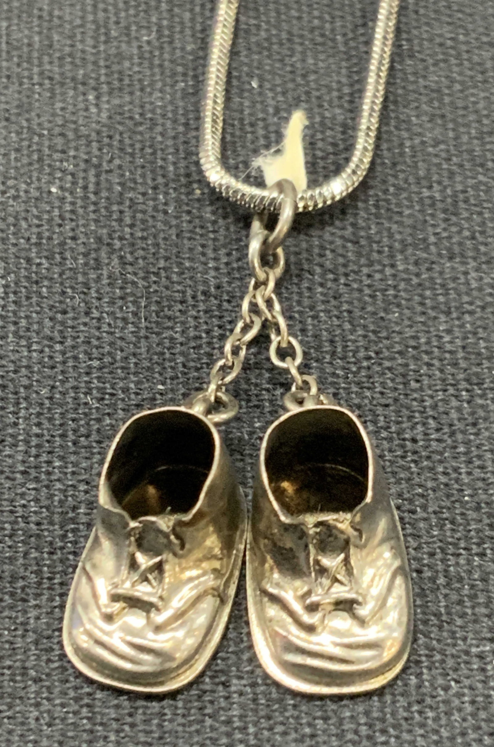 Vntg Sterling Silver Baby Shoe Pendant Necklace: Vintage necklace with sterling silver pendants of baby shoes, marked Sterling and a stainless steel snake chain. Approx 7.5 inches and baby shoes measure 1 inch long Total weight of sterling is 0.04 o