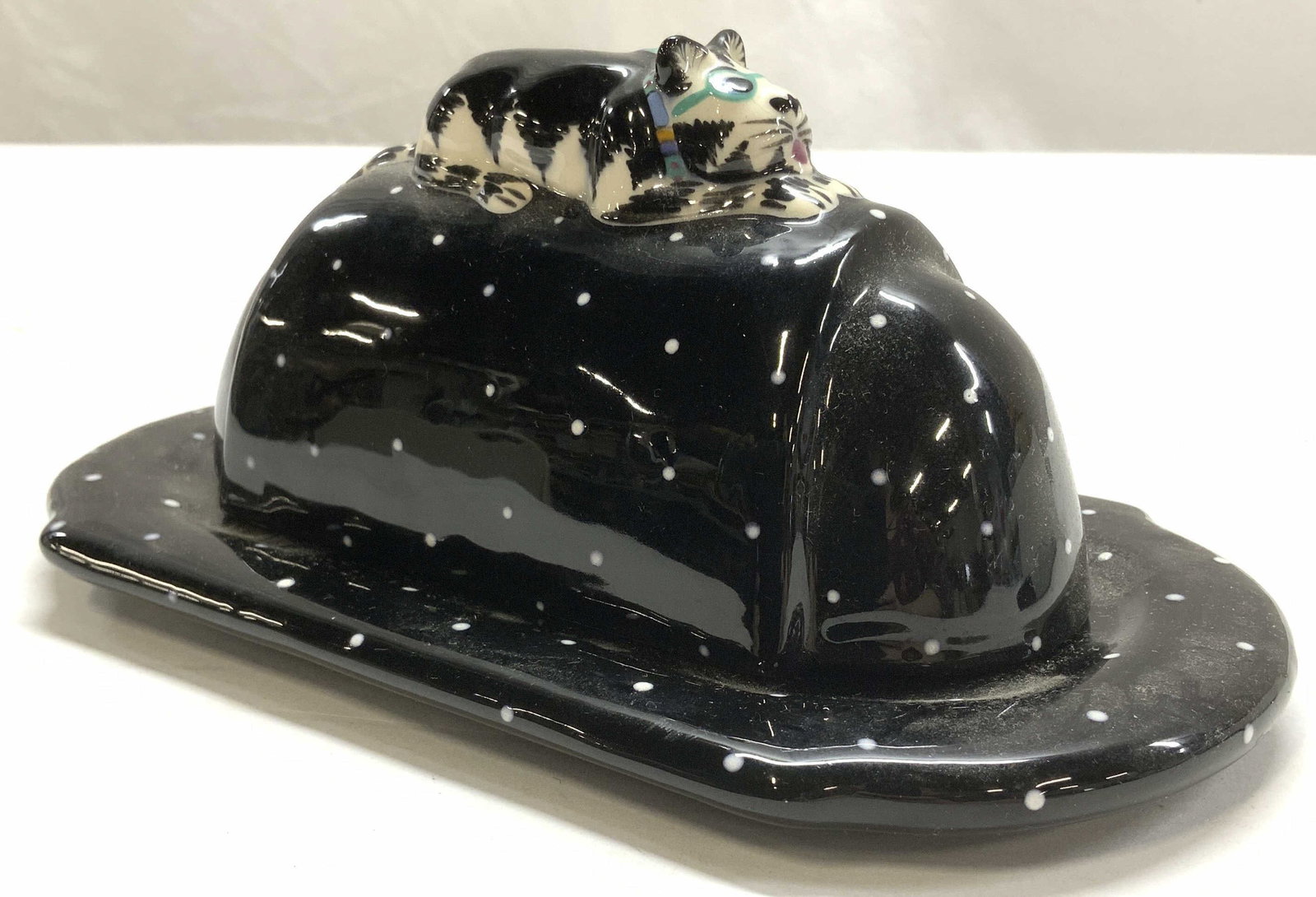 Signed Hatton Folk Art Cat Porcelain Butter Dish: Black porcelain covered butter dish with folk art black and white cat atop. Signed Hatton. Bottom dish measures 8.5 x 4.5 in., height approx 3.5 in. Signed pottery, signed Hatton Porcelain covered but