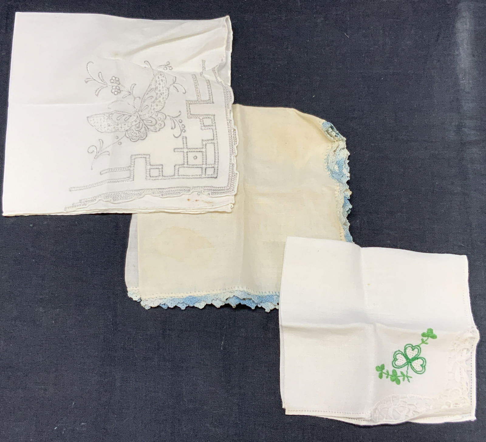 Lot 3 Vntg Embroidered Linen & Lace Handkerchiefs: Lot of 3 vintage linens with embroidery and lace. 1 linen with green embroidered shamrocks on corner with lace, approx 9 x 9.5 inches An off white linen with blue lace edges approx, 11 x 11 inches and