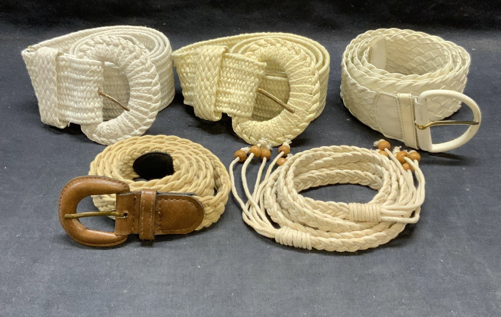 Lot 5 White & Tan Woven Braided Belts: Lot of 5 white and tan toned woven/braided belts. Synthetic material and leather. Longest belt measures approx. 63 inches long. All pieces have some wear to ,arterial consistent with exposure. Ladies 