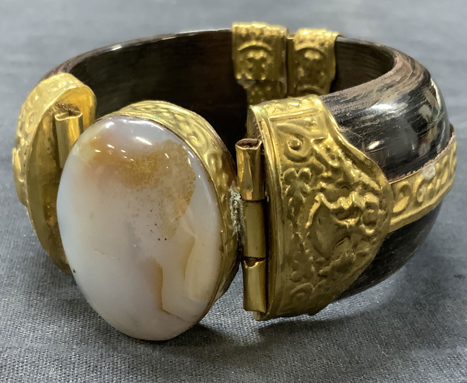 Carved Wood, Brass & Agate Bracelet, India: Carved wooden made bracelet, possibly made of bone with sheet metal embossed with designs and with an agate stone in the center. Approx 2.75 inch diameter with a 1.5 inch thickness and stone being 1.7