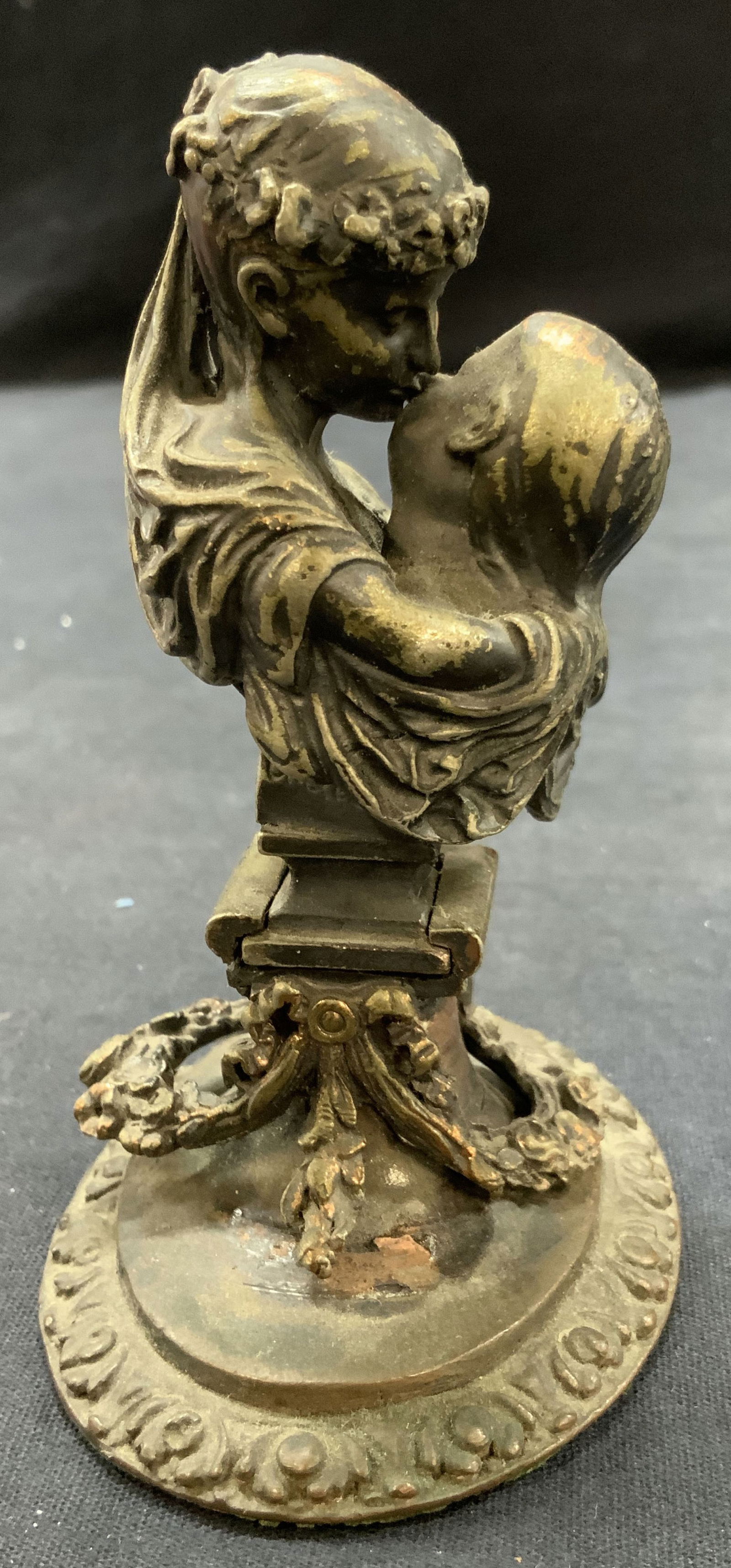 Gilt Copper Mother & Child Figure: Mother and child figure made of patina metal, possibly copper or brass based in undertones of patina Depicting a mother kissing her childs face with wreaths of flowers and the mother wearing a flower