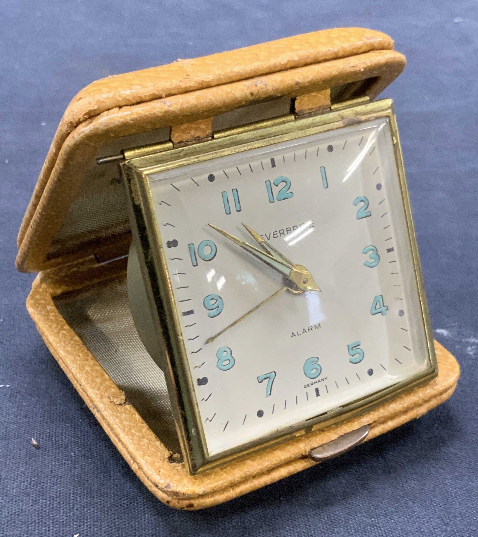 Vntg Everbrite Travel Alarm Clock, Germany: Vintage travel alarm clock. With tan toned leather casing and brass backing to clock. Marked on clock face reading Everbrite, Alarm, Germany. Approx 3 x 3 inches and opened is 3.18 inches tall. Eviden