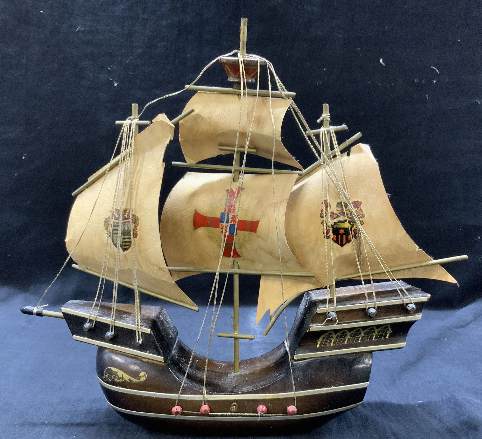 Carved Wooden Hand Painted Ship Model, Holland: Vintage wooden ship figure, with finished carved wooden ship with brass metal accents on one side and hand painted gold motifs. Sails are made with parchment paper with pressed shield designs on each.