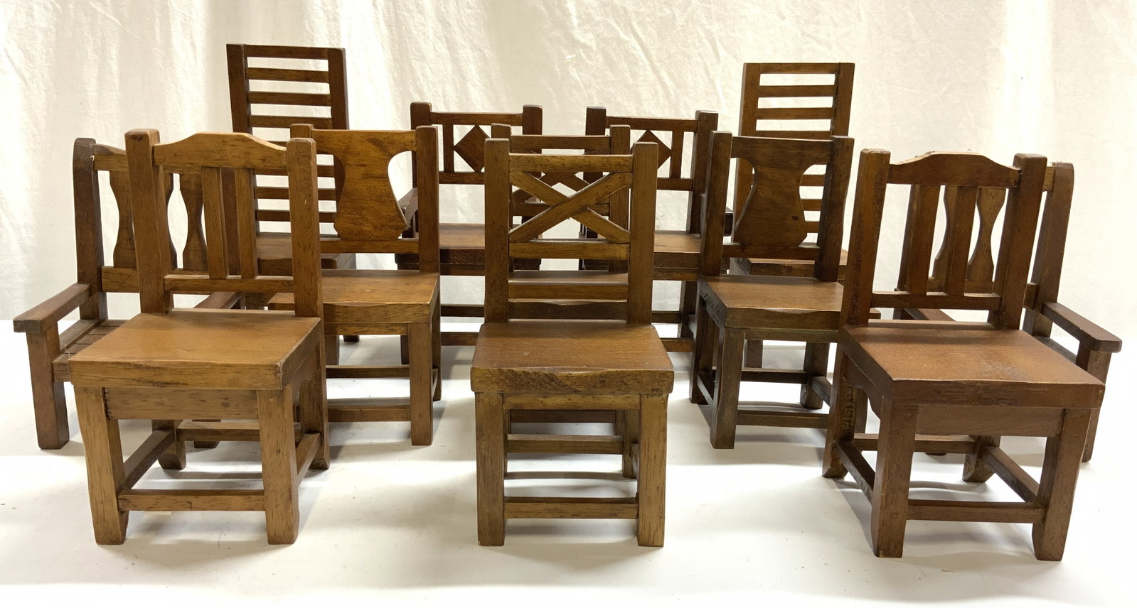 Lot 12 Vintage Carved Wooden Doll Chairs: Doll chairs appear to be wooden possibly wood veneer. Chairs are each brown toned. Four chairs have arms 8 are side chairs. Largest chairs measure approx 12 inches tall 4.5 inches wide & deep. Chairs,