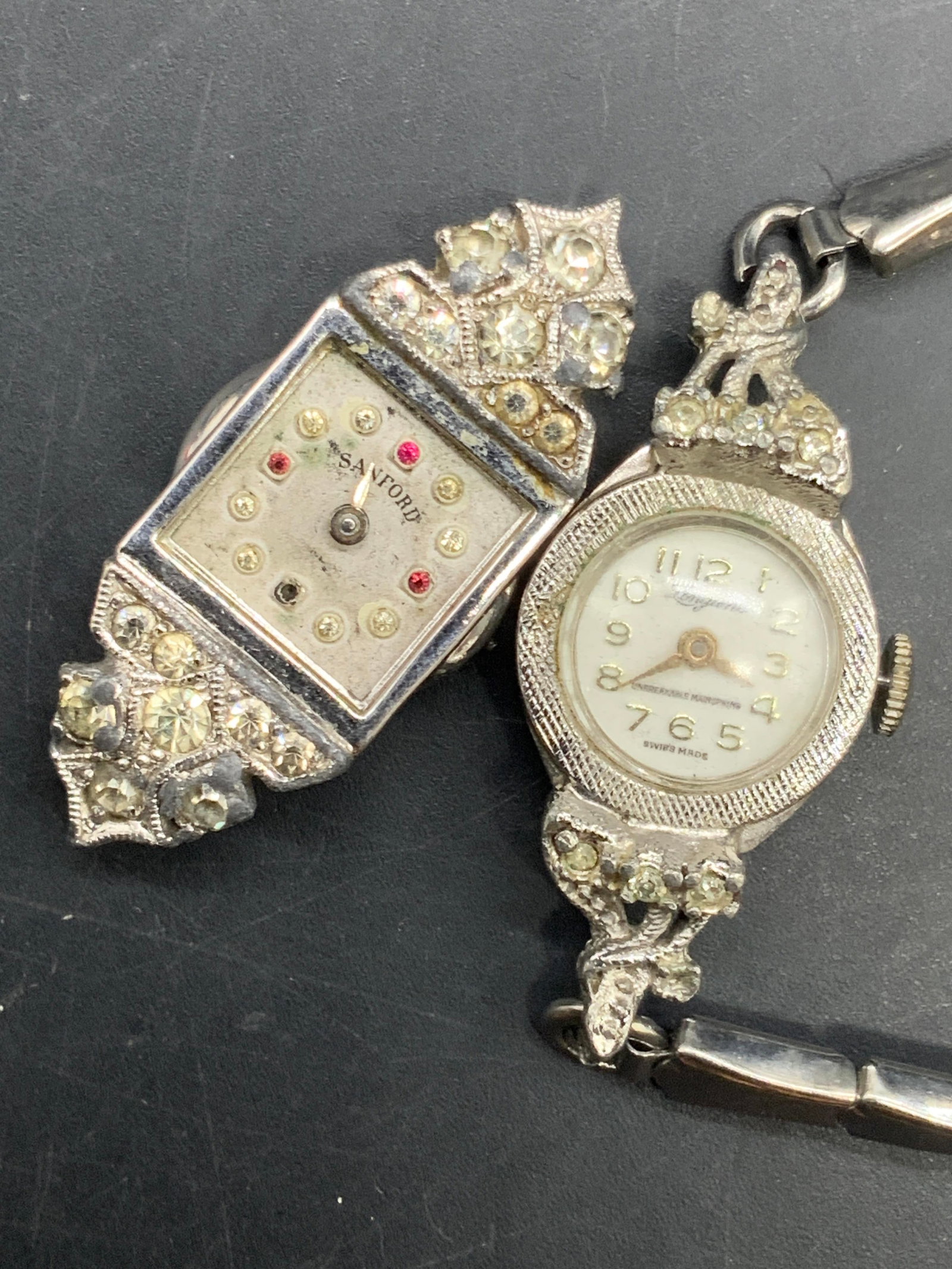Lot 2 Vntg LONGUNE Watch & SANFORD Watch Face: A lot consisting of one LONGUNES Swiss Made silver tone metal stretch watch and a bejeweled SANFORD watch face. Diameter of LONGUNES Watch approx. 2 inches. SANFORD measures approx. 1.5L x .5W in. Pie