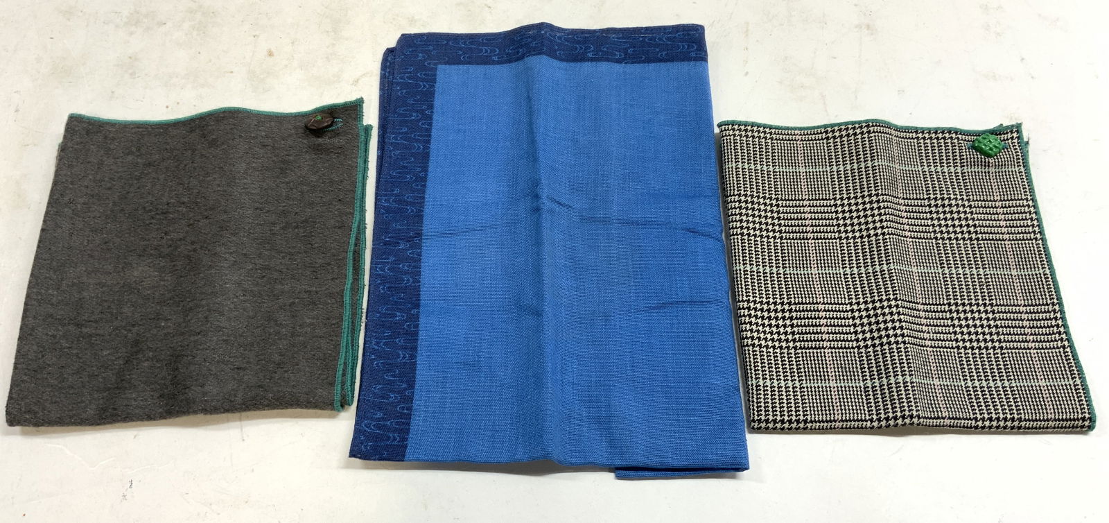 Lot 3 Pocket Squares, Houndstooth & More: Lot includes 1 houndstooth, 1 slate toned with teal edges, and 1 blue toned pocket square. Two out of the 3 have buttons. Largest measures approx 18 inches square. Pocket squares, textiles, fashion ac