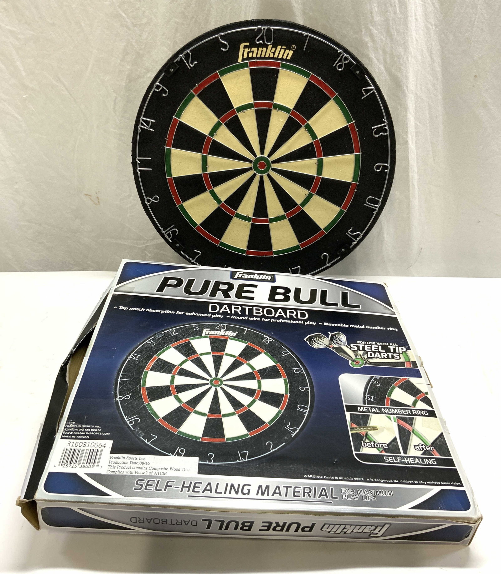 FRANKLIN PURE BULL Dartboard In Box W Darts: Box reads Franklin Pure Bull Dartboard. Lot includes dartboard, 3 red, and 3 black toned darts. Dartboard includes box. Dartboard measures approx 18 inches diameter. Dartboard, Franklin Dartboard, Fra