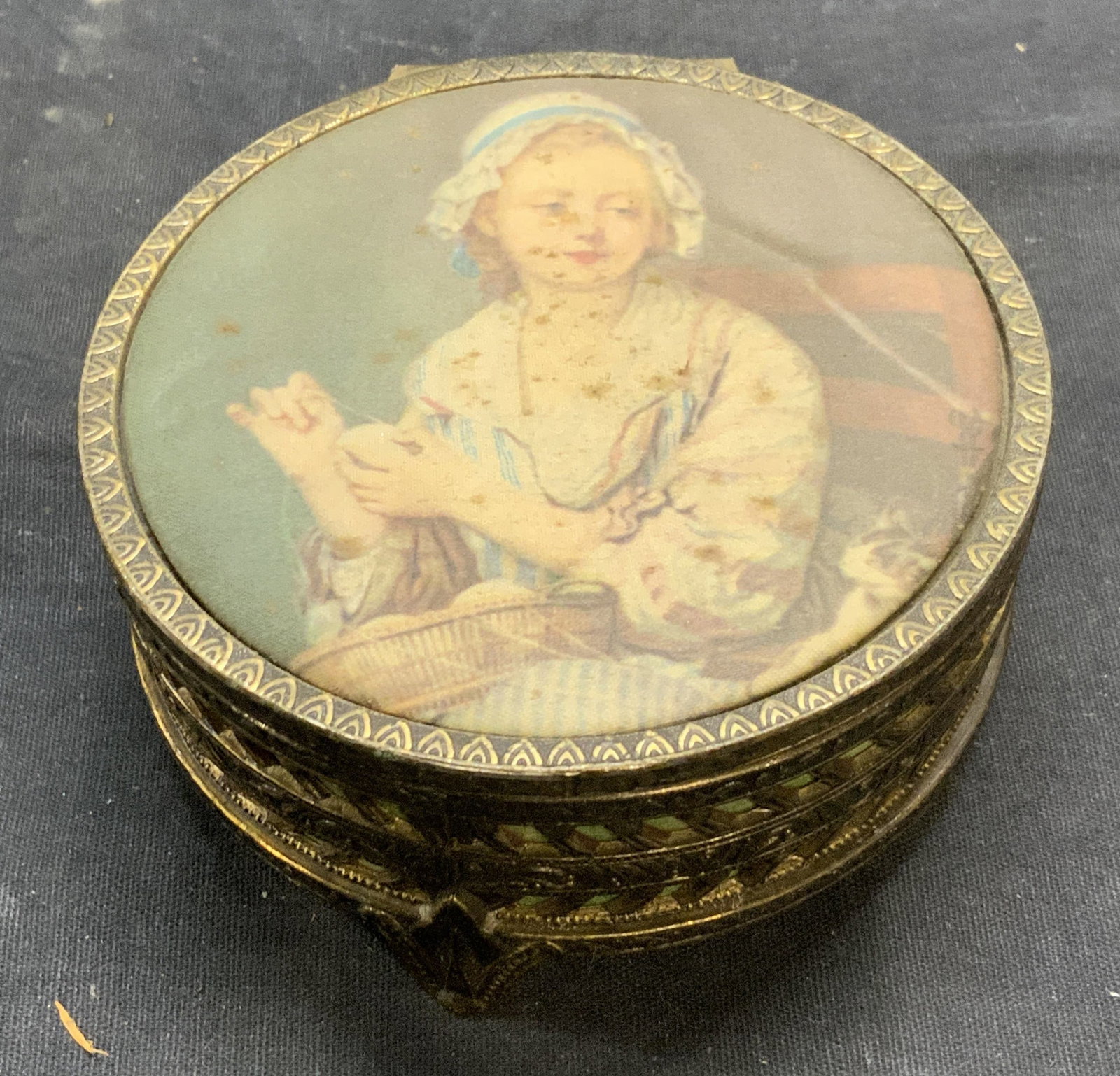 Vintage Greuze Wool Winder Jewelry Box: Vintage silver plated jewelry box with silk covered lid. Wool Winder by John Bartiste Greuze on lid. Velvet lined interior. Measure approx. 4 x 1.75 inches. Lid needs repair. Surface wear including lo