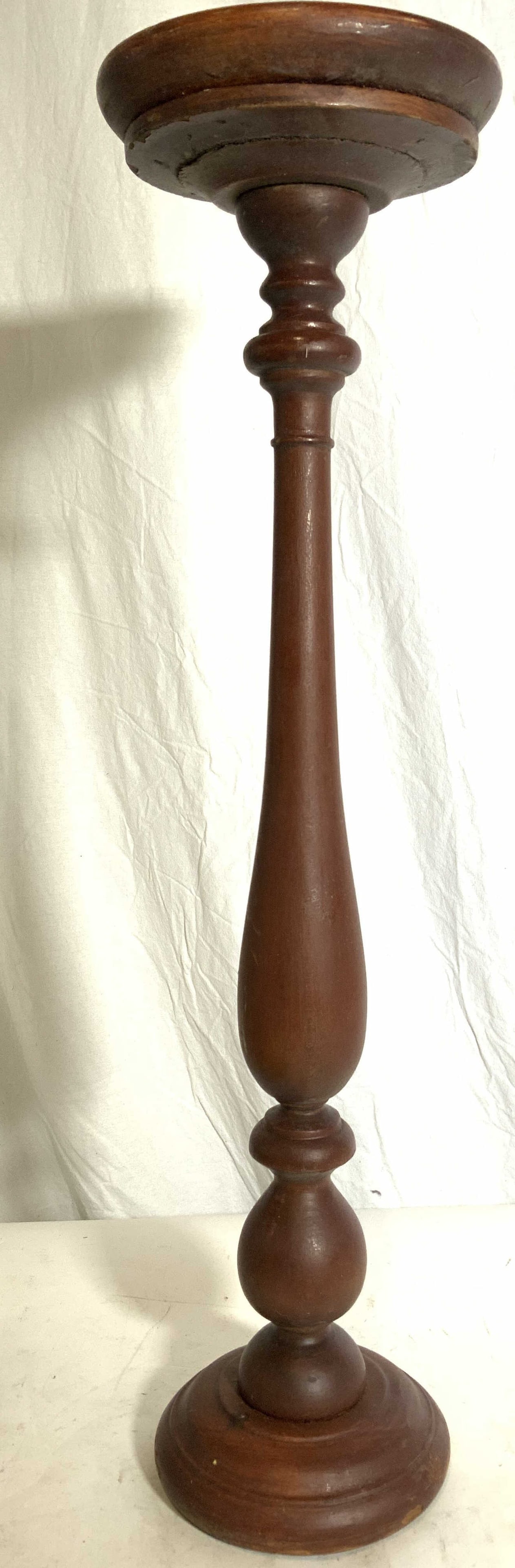 Vintage Carved Wooden Floor Size Candlestick: Candlestick is vintage and wooden. Piece has circular shaped base. Candlestick has a burgundy brown tone. Piece measures approx 26 inches tall 6 inches wide. Candlestick, vintage candlestick, carved w