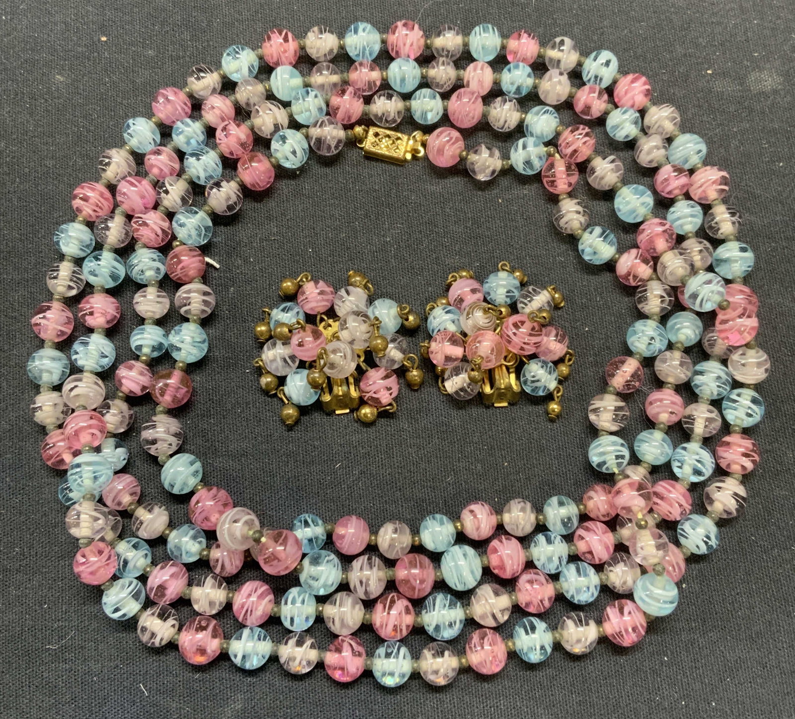 Beaded Art Glass Necklace & Earring Set: Matching purple, pink, and clear toned art glass beaded necklace and clip on earring set. Necklace drop length approx. 30 inches. Earrings measure approx. 1inch wide. Some scratching observed. Estate 