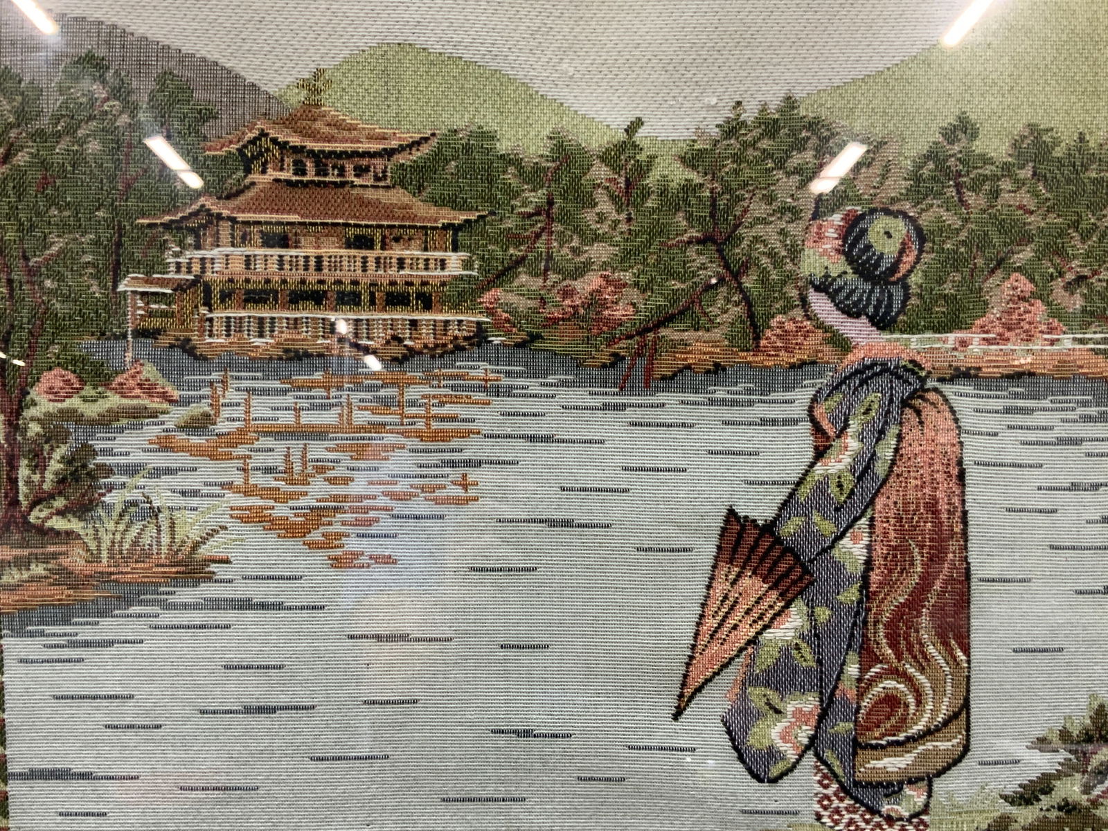 Vntg Kinkaku Woven Silk Asian Framed Fabric Art: Vintage woven silk framed tapestry, marked Kyoto, Kinkaku, depicting the Buddhist temple in the river with a forest around and a geisha in the foreground. Framed in a black wooden frame with green mat