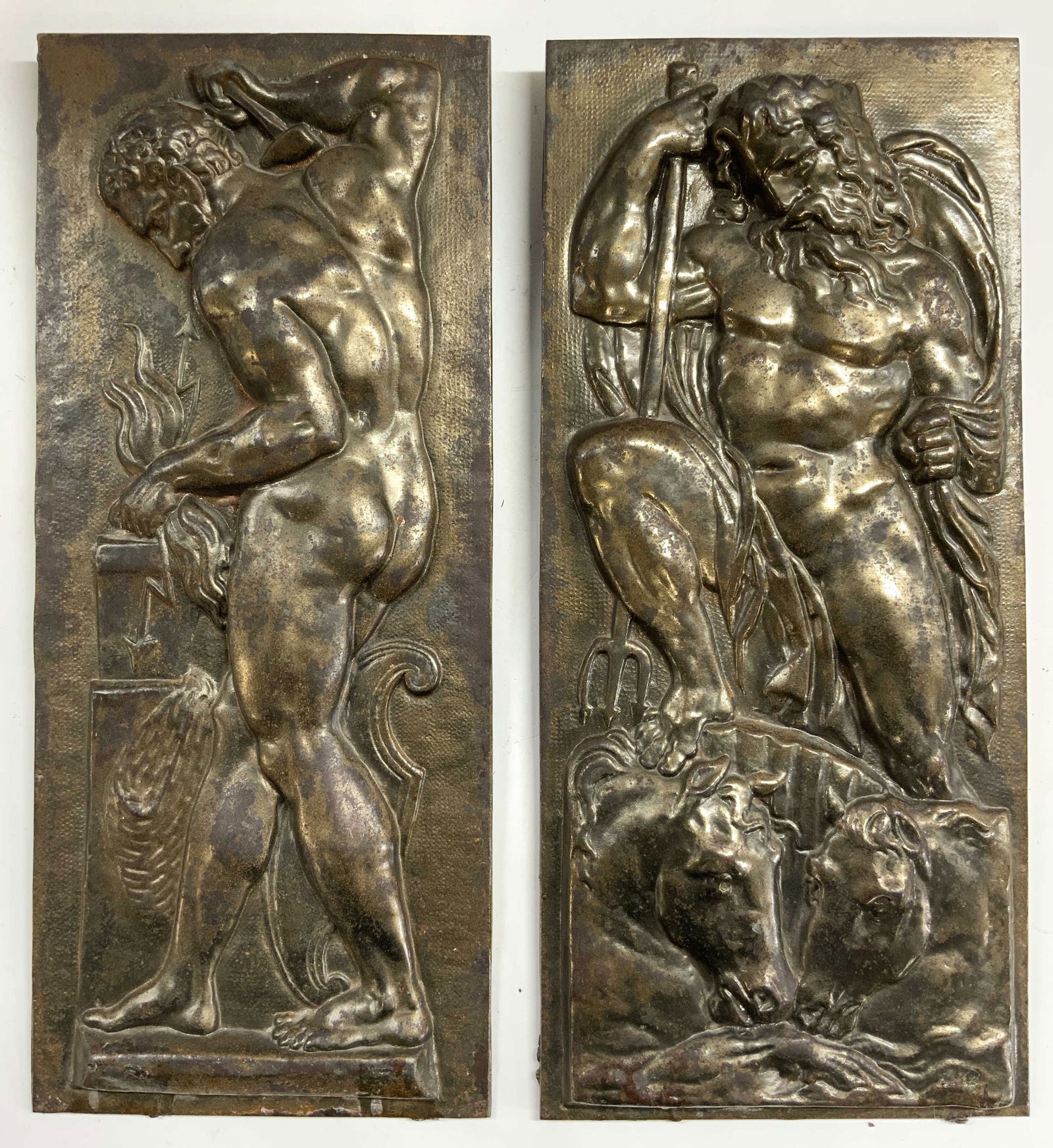 Lot 2 Vntg Poseidon & Vulcan Iron Repousse Reliefs: Lot Includes 2 repousse reliefs. Each appear to be iron, possibly brass. Depicting beveled male nude figures. One with trident standing on top of horse heads, one figure with backside turned holding w