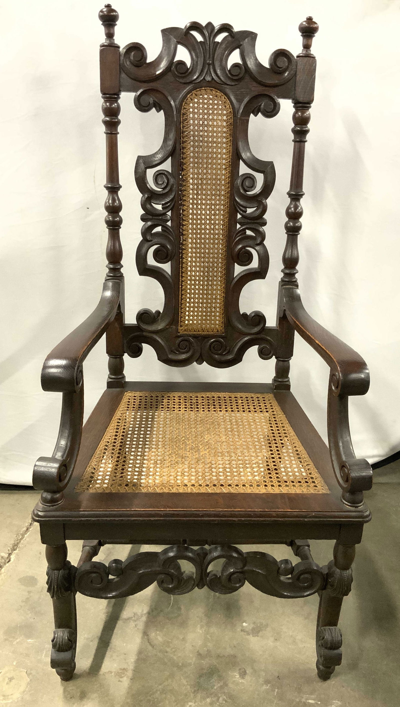 Antq Wooden Jacobean Renaissance Revival Chair: Chair is antique and wooden. Piece appears to be Jacobean Renaissance Revival. Chair is wooden. Piece has intricately carved scroll detail. Chair has caned backrest & seat. Chair has H form stretcher