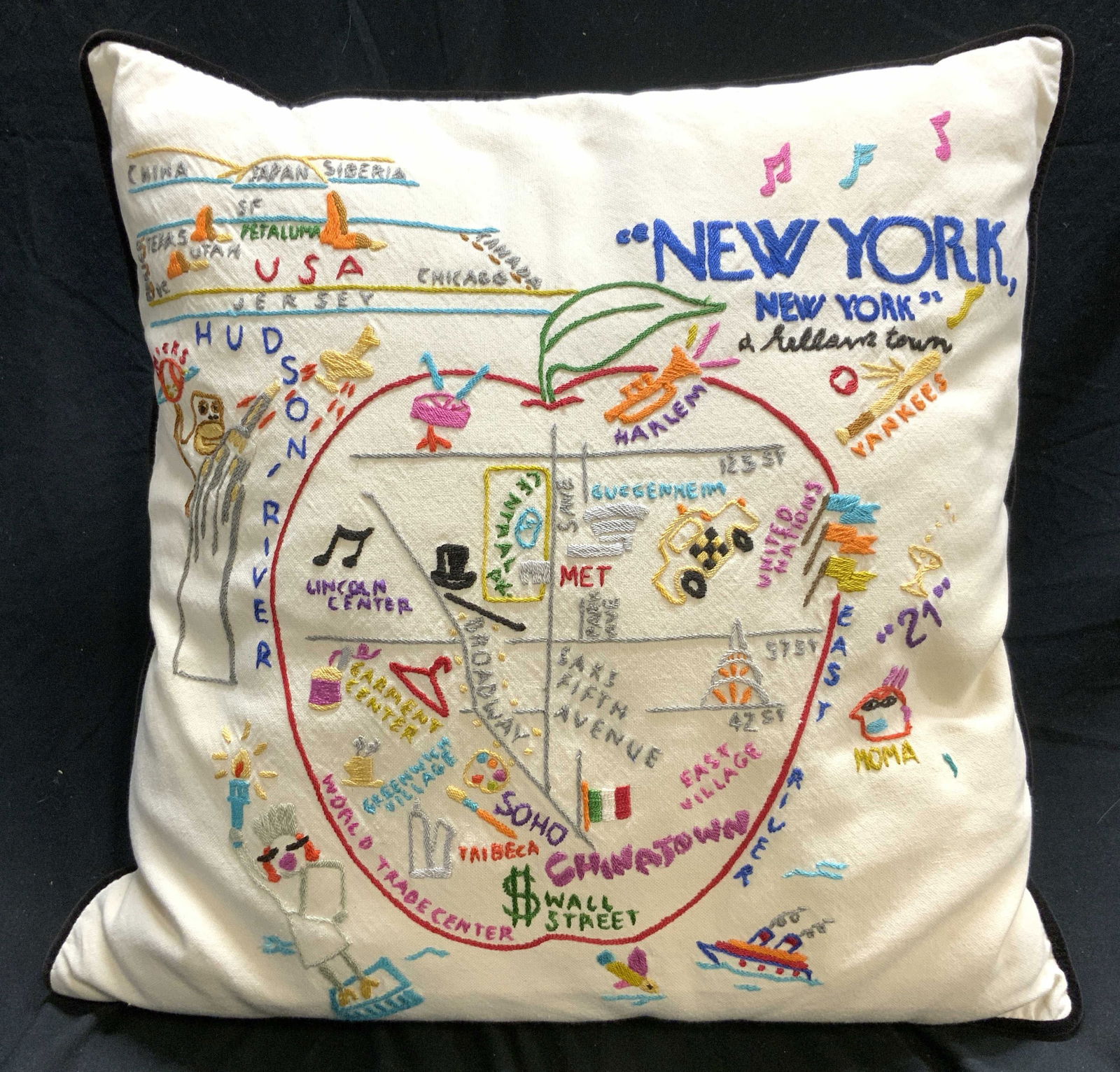 CATSTUDIO NEW YORK Embroidered Pillow: Tag reads CATSTUDIO. Pillow has multi toned embroidered detail, apple, Statue of Liberty, taxi and more. Pillow is cream toned with black welted edges. Piece measures approximately 17.5 inches square