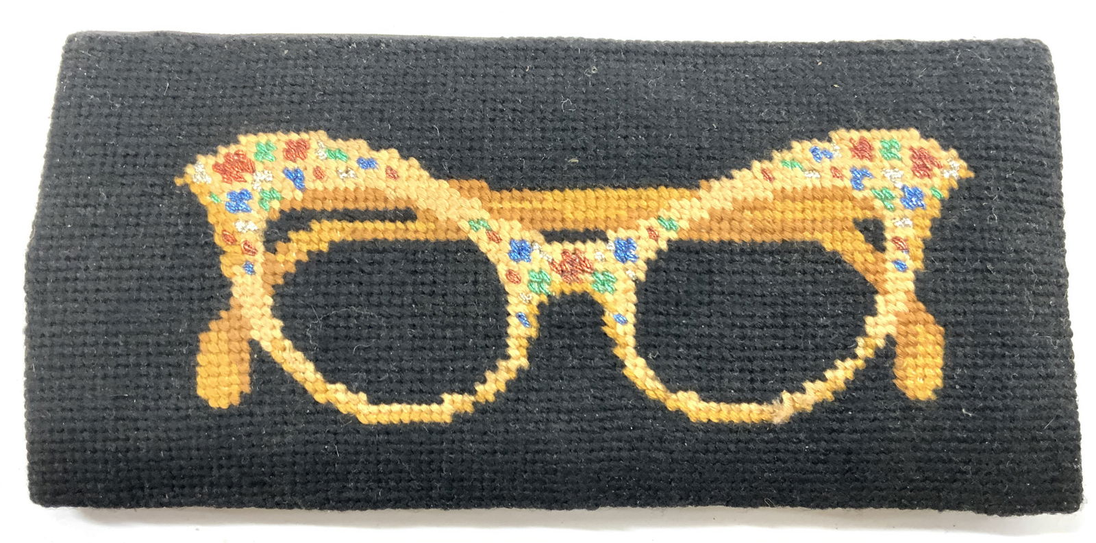 Vintage Woven Needlepoint Glasses Case: Eye glass case is vintage. Piece is needlepoint with depiction of a pair of glasses with multi toned detail. Case is black toned. Piece measures approximately 6.5 inches long 3 inches wide. Glasses ca