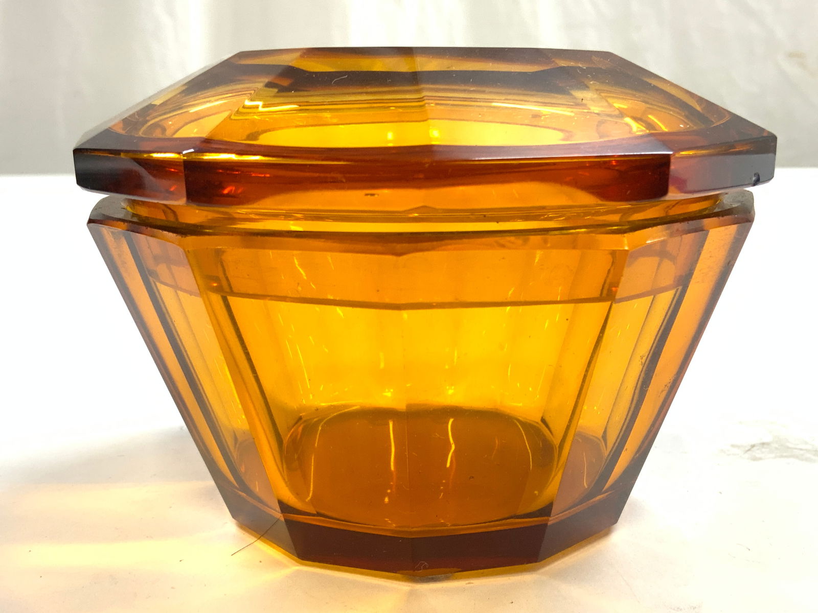 Vintage Amber Glass Vessel With Lid: Vessel is amber glass. Piece includes lid. Vessel appears to be vintage. Piece has geometrical form. Piece measures approximately 5 inches wide 3.25 inches tall. Vessel, Art glass, art glass vessel, a