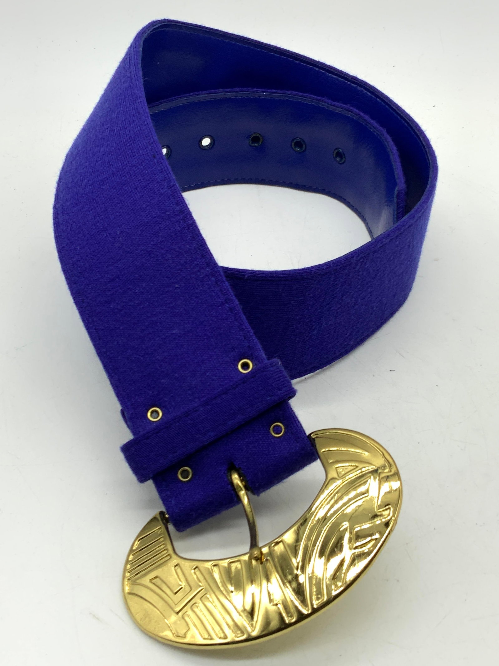 Blue Leather Style Fashion Belt: Blue toned fashion belt with fabric on outer band and leather style nylon on underside and a gold toned metal buckle with pressed designs on buckle. Approx 32 inches long and 2 inches wide. Minor wear