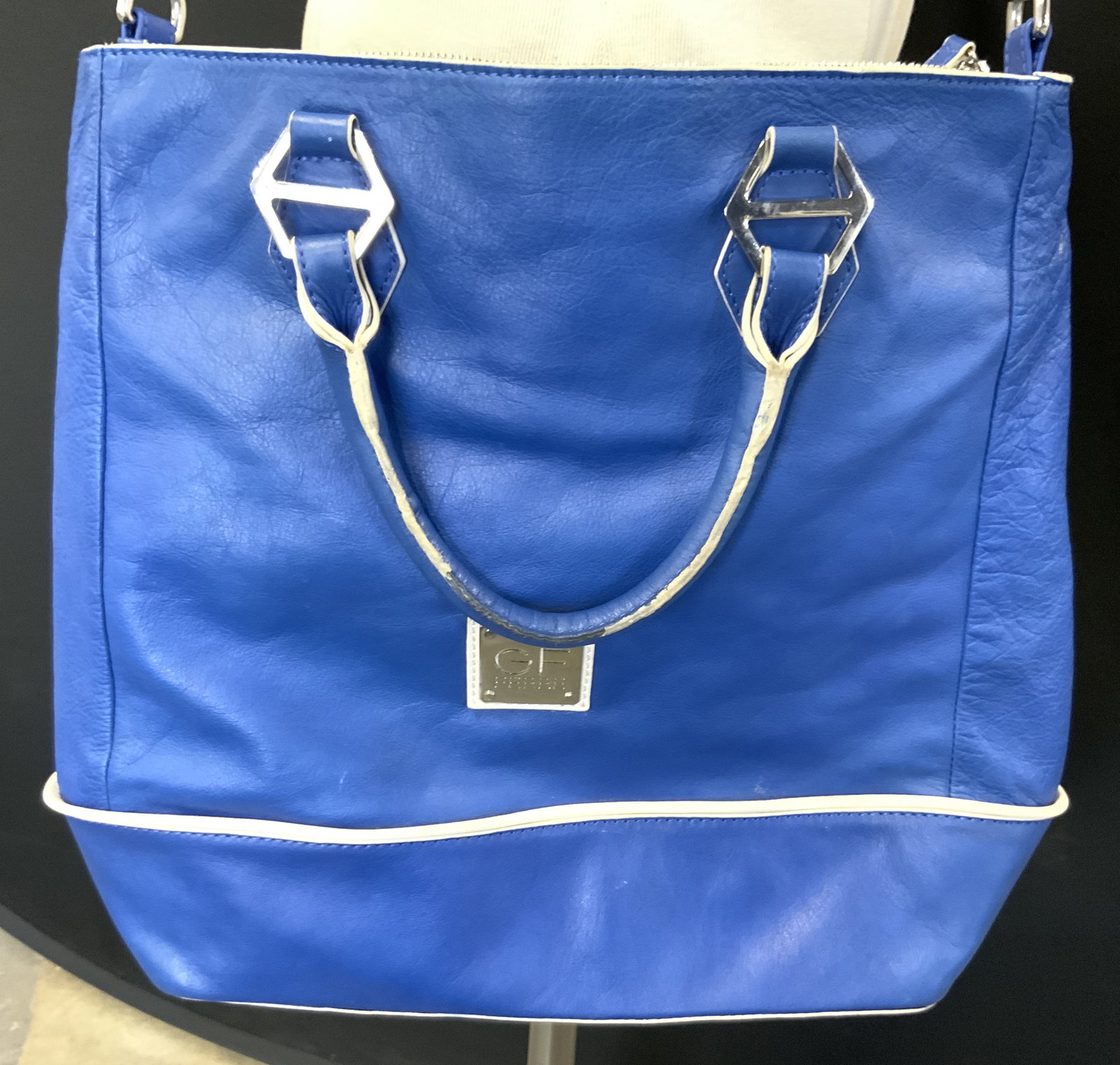 GF FERRE Leather Tote with Crossbody Blue: Trademarked plaque reads GF FERRE. Tote is blue with white toned accents & silver toned metal hardware. Piece has handles and crossbody strap. Tote is leather. Interior has 1 zippered pocket and 2 poc