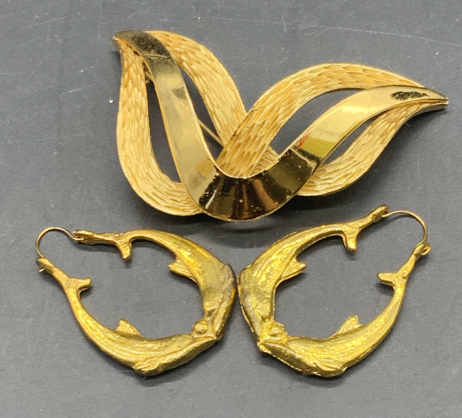 Lot 2 TRIFARI Vintage Sculptural Brooch & Earrings: Vintage sculptural brooch is crafted from polished and textured gold tone metal brooch and signed TRIFARI to underside. Metal pin closure to underside. Measures approx. 2.5W x 1.5L in. Vintage earring