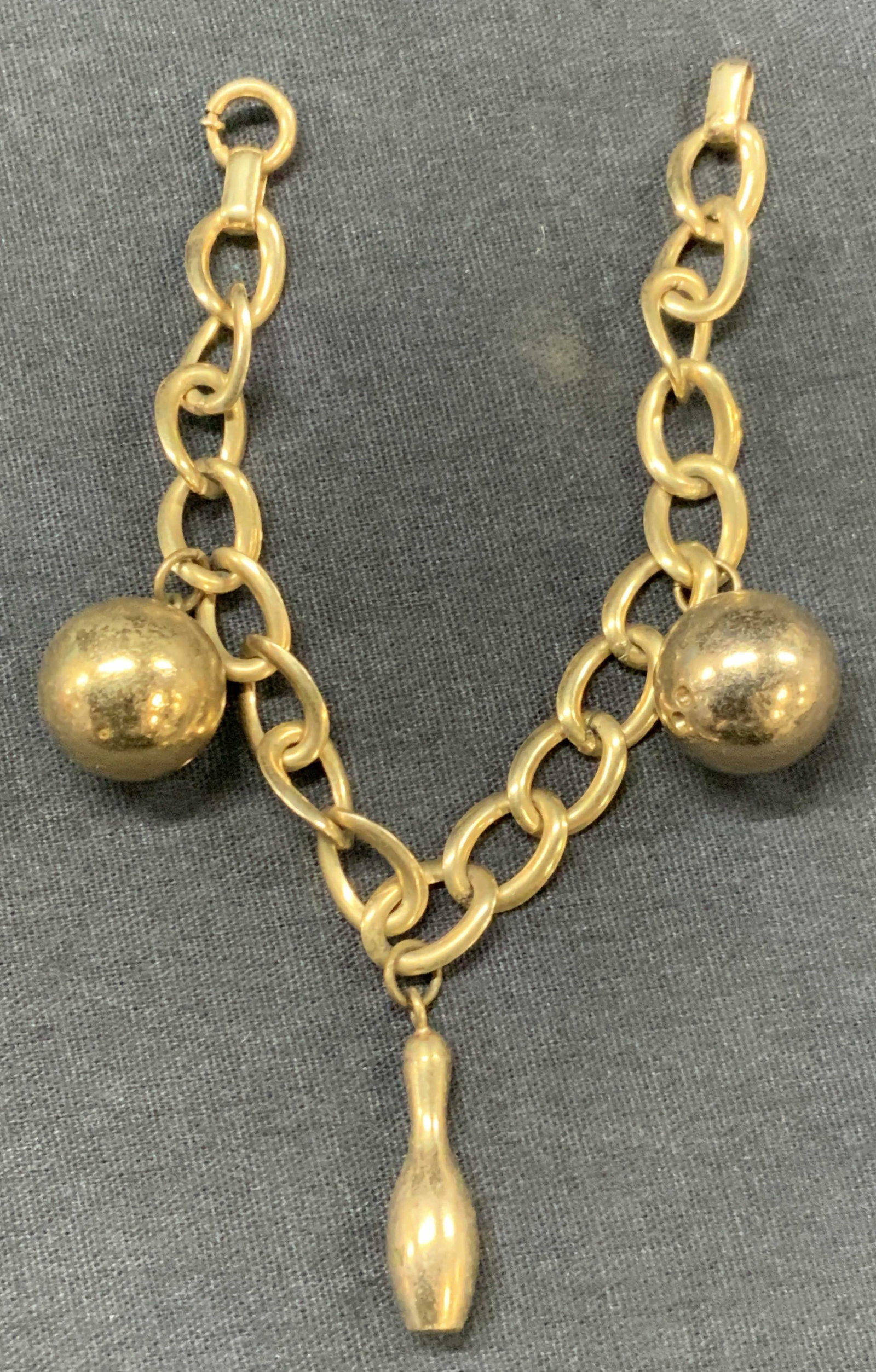 12 K Golf Filled Bowling Charm Bracelet: Marked on bracelets, 1-20 12 k GF Bab Gold filled chain bracelet with bowling charms of bowling balls and a pin. Approx 7 inches long. Charms art 1.25 inches long. Clasp to bracelet has difficulty ope