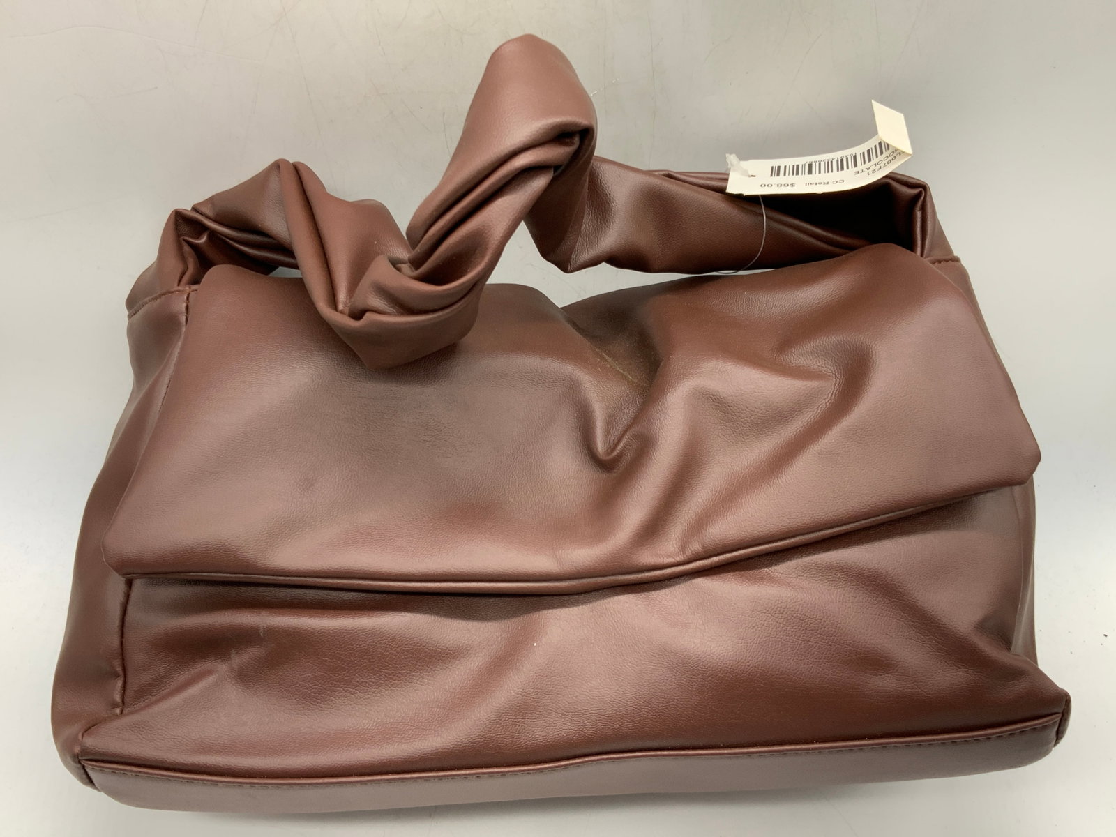 Chocolate Tn Faux Leather Shoulder Bag: Chocolate toned faux leather shoulder bag with twisted strap design and rectangular shape, approx 7 x 13 x 5 inches with strap being 9 inch strap drop. New with tag. Little to no noticeable wearing to