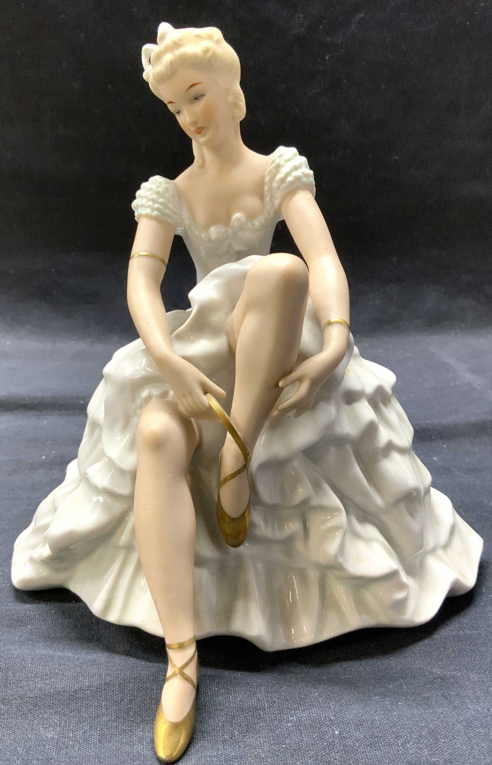 WALLENDORF Vntg Porc Ballerina Figure GERMANY: Underside has W trademark (WALLENDORF) & Reads GERMANY. Depicts a seated female ballerina figure wearing gown & undoing her shoes. Figure is vintage and porcelain. Piece has some gilt areas. Piece mea