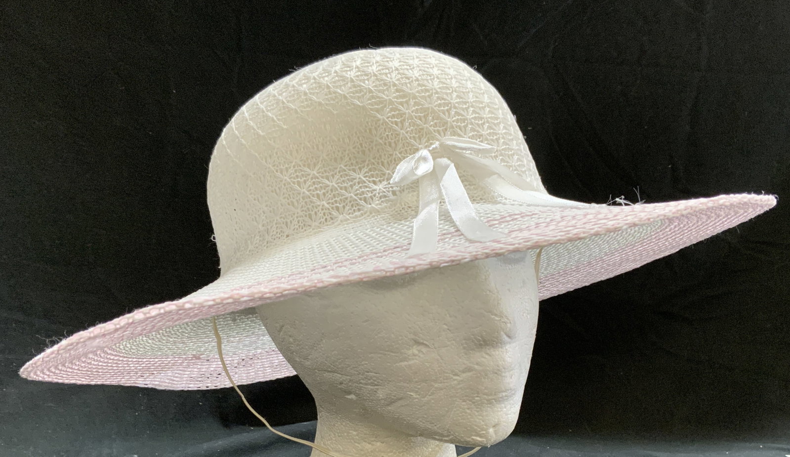 Woven Hat w Ribbon White & Pink: Hat is crafted from woven synthetic material. Hat is white with pink toned brim. Front of hat has ribbon tied into bow. Hat measures approximately 14 inches wide inches tall. Hat, woven hat, white hat