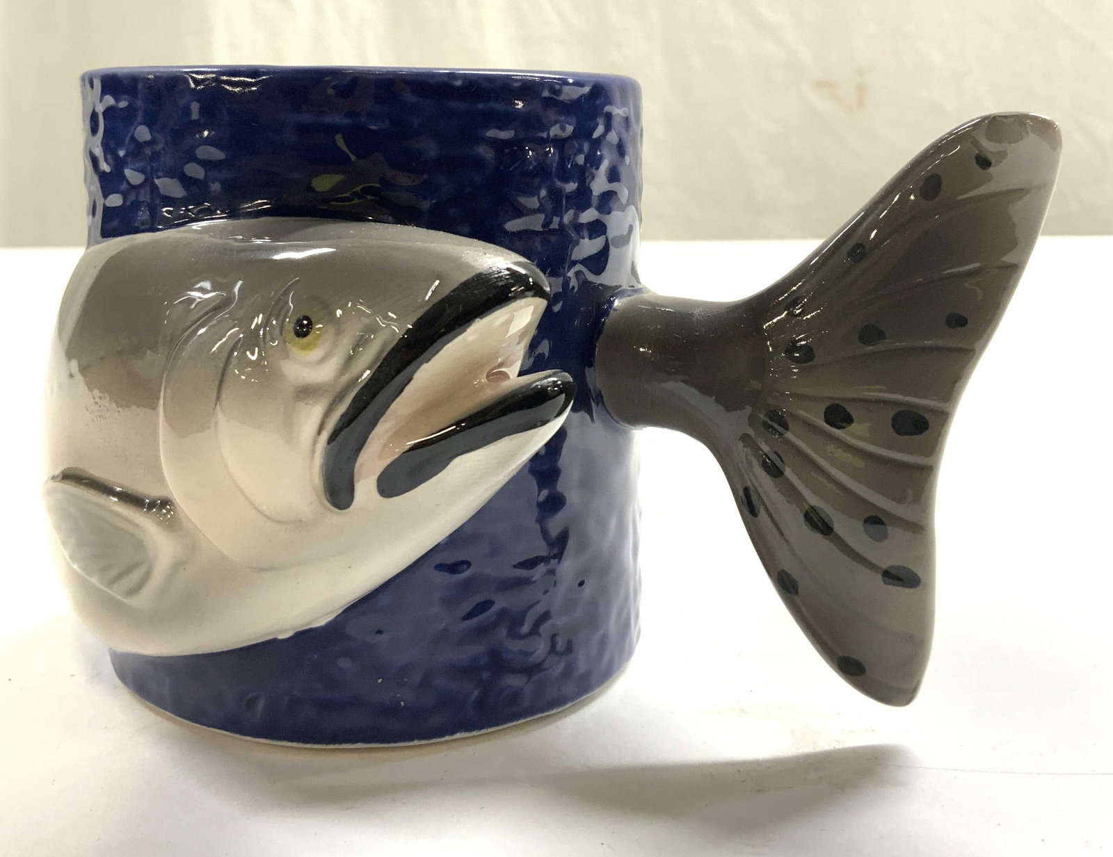 BERGSCHRUND Hand Painted Porc Fish Mug: Underside reads BERGSCHRUND MADE IN SRI LANKA. Mug is hand painted. Piece is porcelain. Mug has fish figure wrapped around structure. Piece measures approximately 3.5 inches tall 6 inches deep 3.75 in