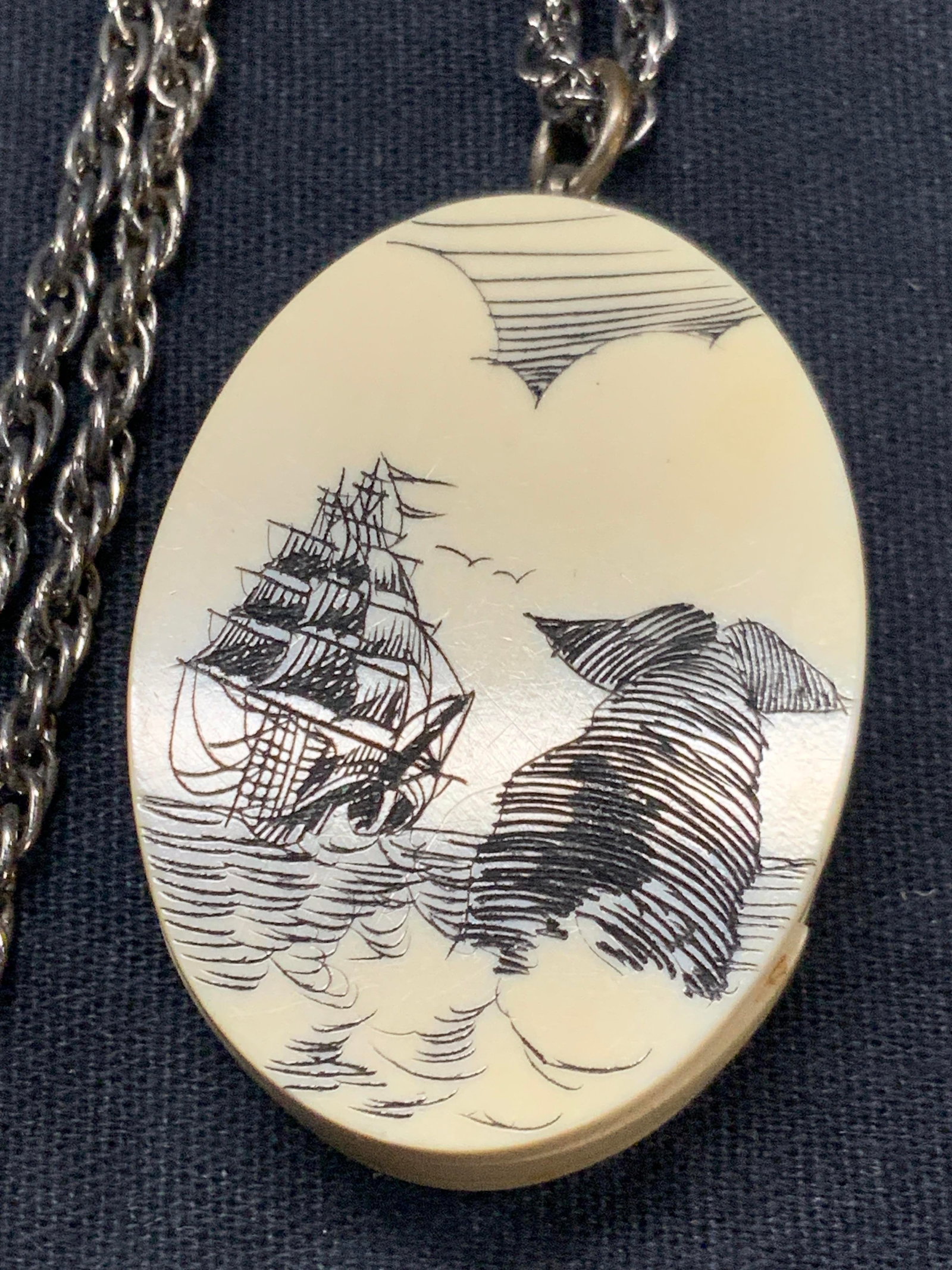 Scrimshaw Etched Bone Pendant Necklace: Scrimshaw etched bone pendant necklace with double sided etchings of a ship on the water and a whale breaching the waves. Approx 11 inches long. Possibly made of bone, possibly resin with center piece