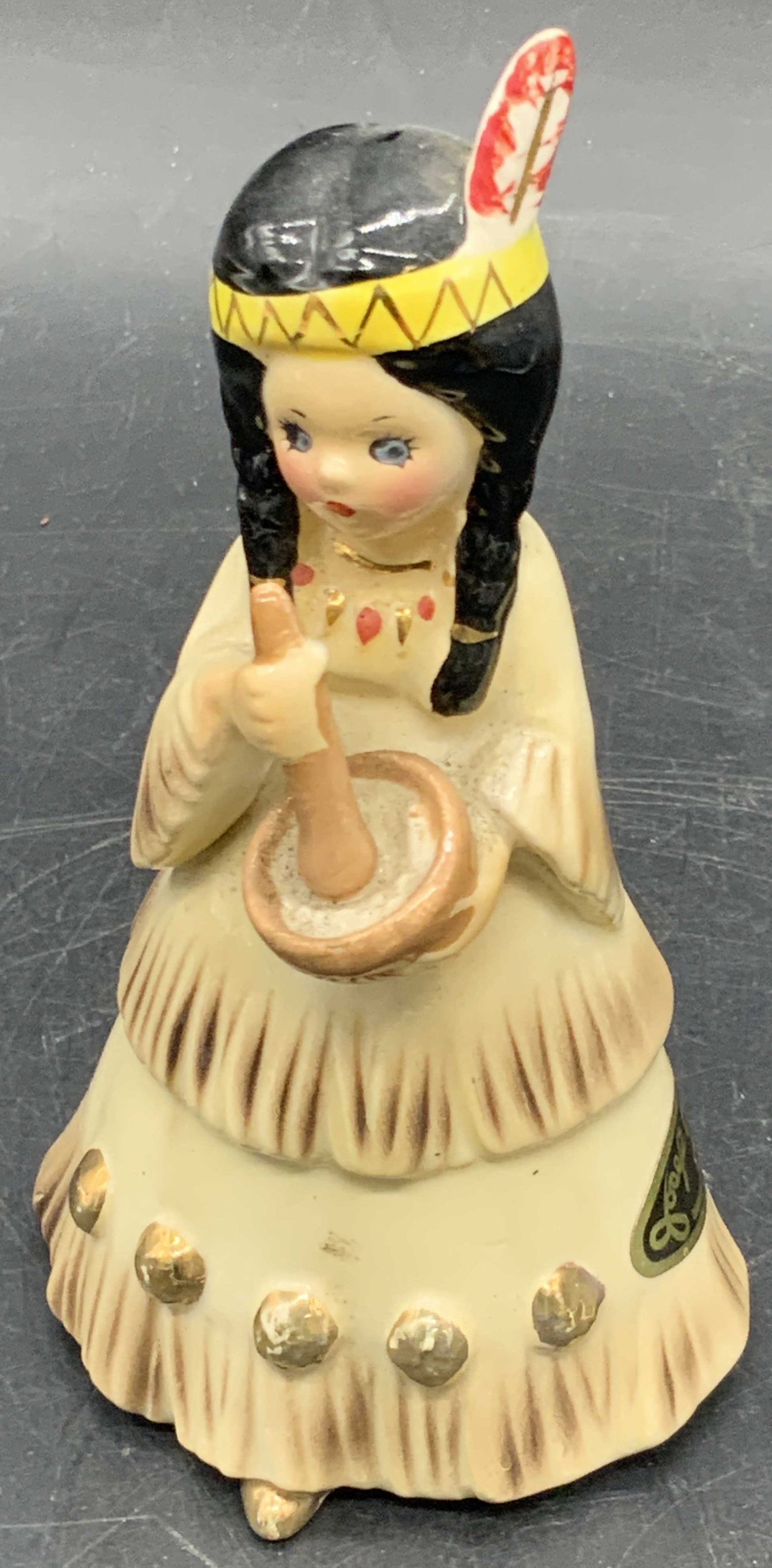 JOSEF ORIGINALS Vintage Ceramic America Figural: A ceramic figural depicting a Native American woman wearing traditional clothing and stirring a handheld pot. Measures approx. 4.5H x 2.5W in. Stickers to underside and side. One sticker reads America