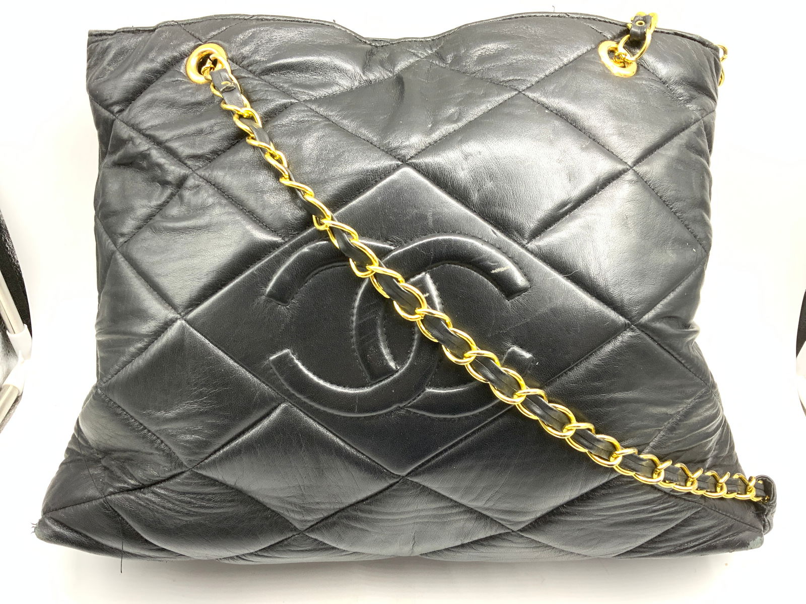 Quilted Leather Shoulder Bag: Quilted leather shoulder bag. Quilted black leather with a stitched interlocking CC on frontside. Woven leather through gold tone chain straps. 16 in drop. Metal has weight.. comfortable leather shoul