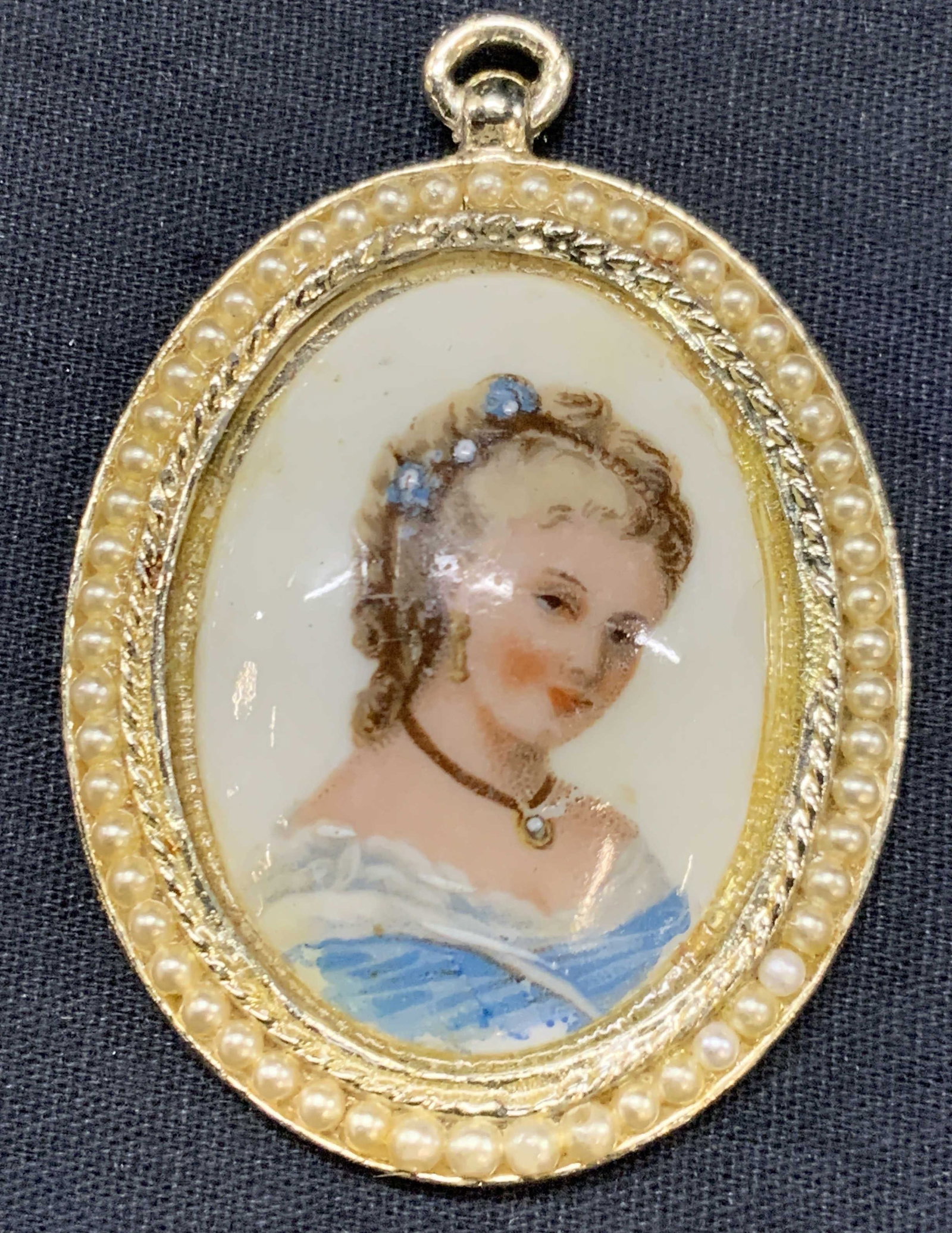 Limoges Portrait On Porcelain Pendant, France: Stamped Limoges, made in France. Printed portrait of a blonde woman in a blue dress on a porcelain. Framed within a gold toned pearlescent encrusted pendant. Approx 2.75 x 2 inches. Evident repairing 