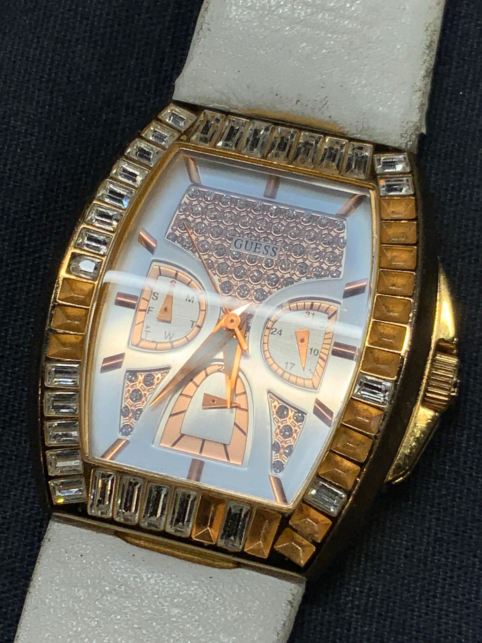 Guess Gold Th & Leather Wrist Watch: Guess brand wrist watch with genuine white tone leather hand. Halo encrusted faceted crystals around watch face with days of the week and other measurements on face. Approx 9 inches long and watch fac